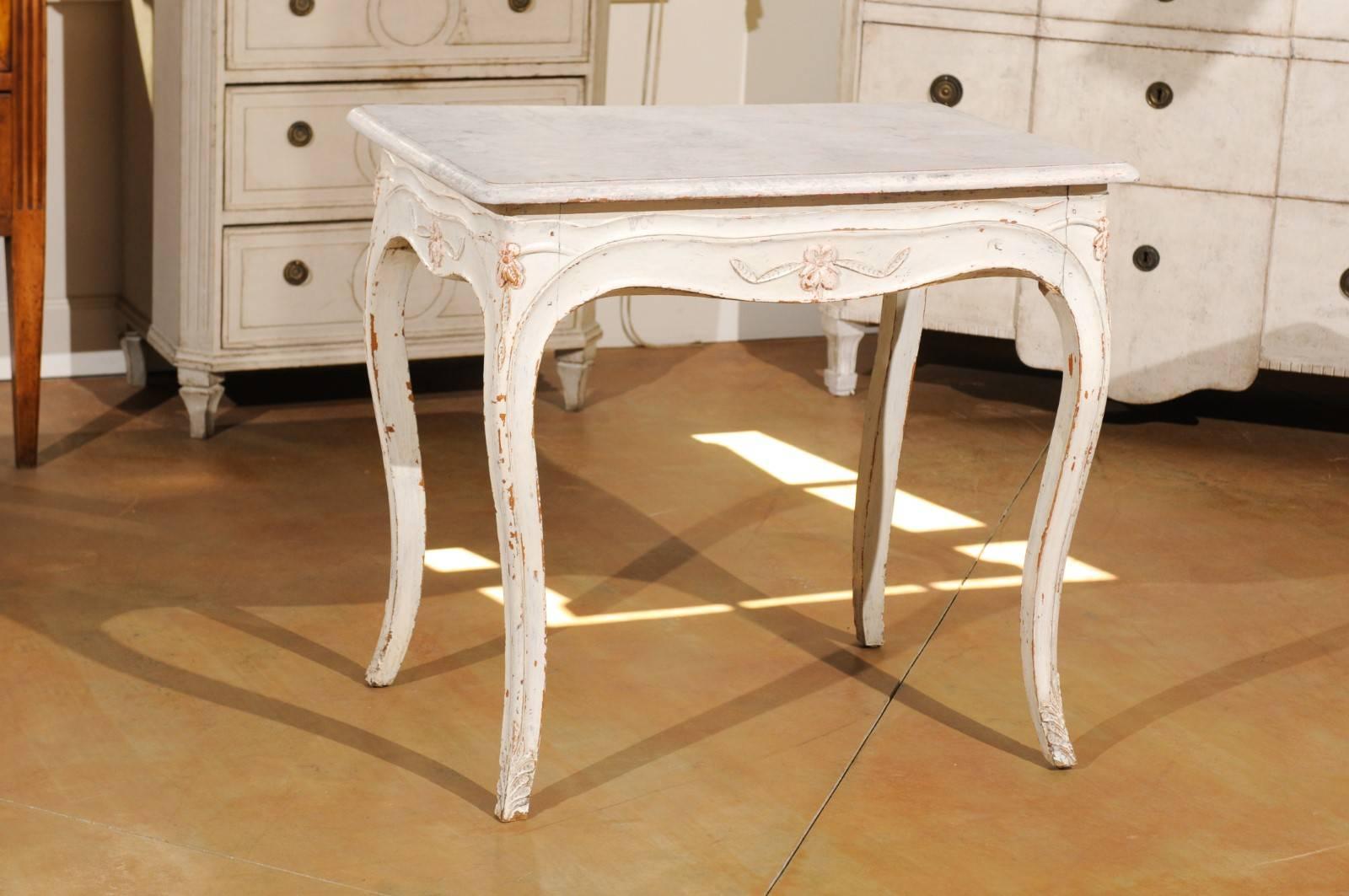 A Swedish painted freestanding side table from the late 19th century with carved apron and cabriole legs. This Swedish side table features a rectangular top with bevelled edges, sitting above an apron beautifully carved on all sides. This valanced