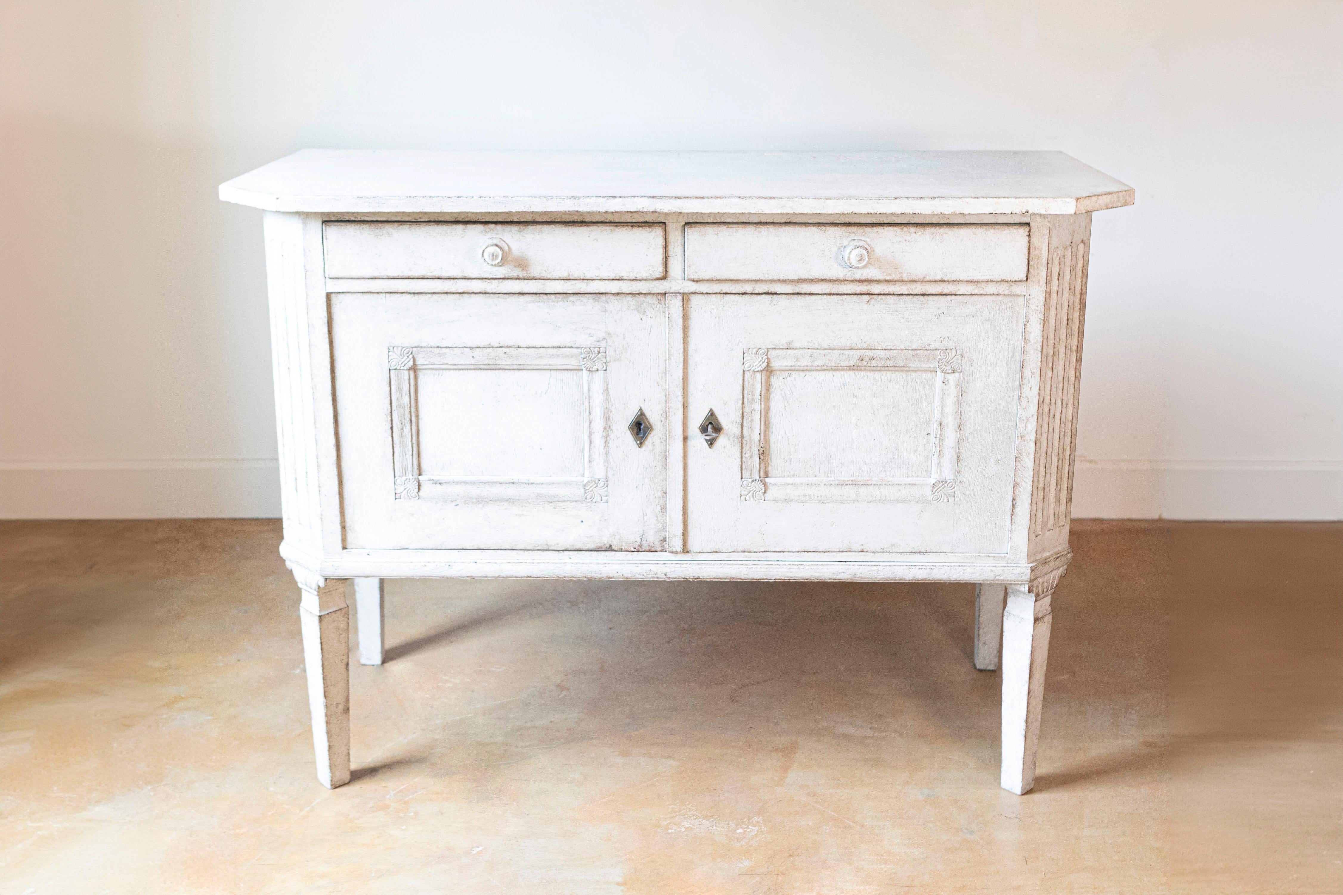 A Swedish painted wood sideboard from the late 19th century, with two drawers, two doors, canted side posts and tapered legs. Born in Sweden in the last decade of the 19th century, this painted sideboard features a rectangular top with canted