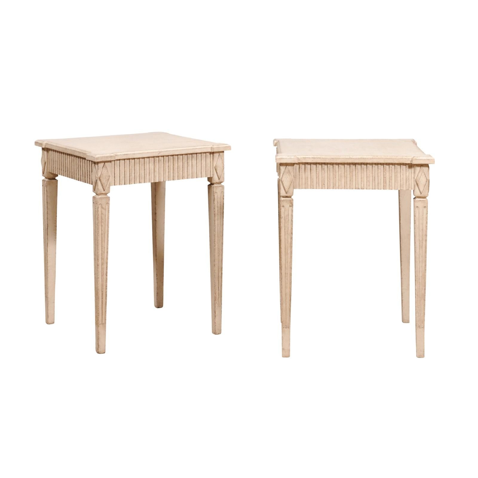 A pair of Swedish console tables from circa 1890 with light creamy yellow paint, carved aprons, diamond motifs and tapering fluted legs. This exquisite pair of Swedish console tables, dating back to circa 1890, embodies the timeless elegance and