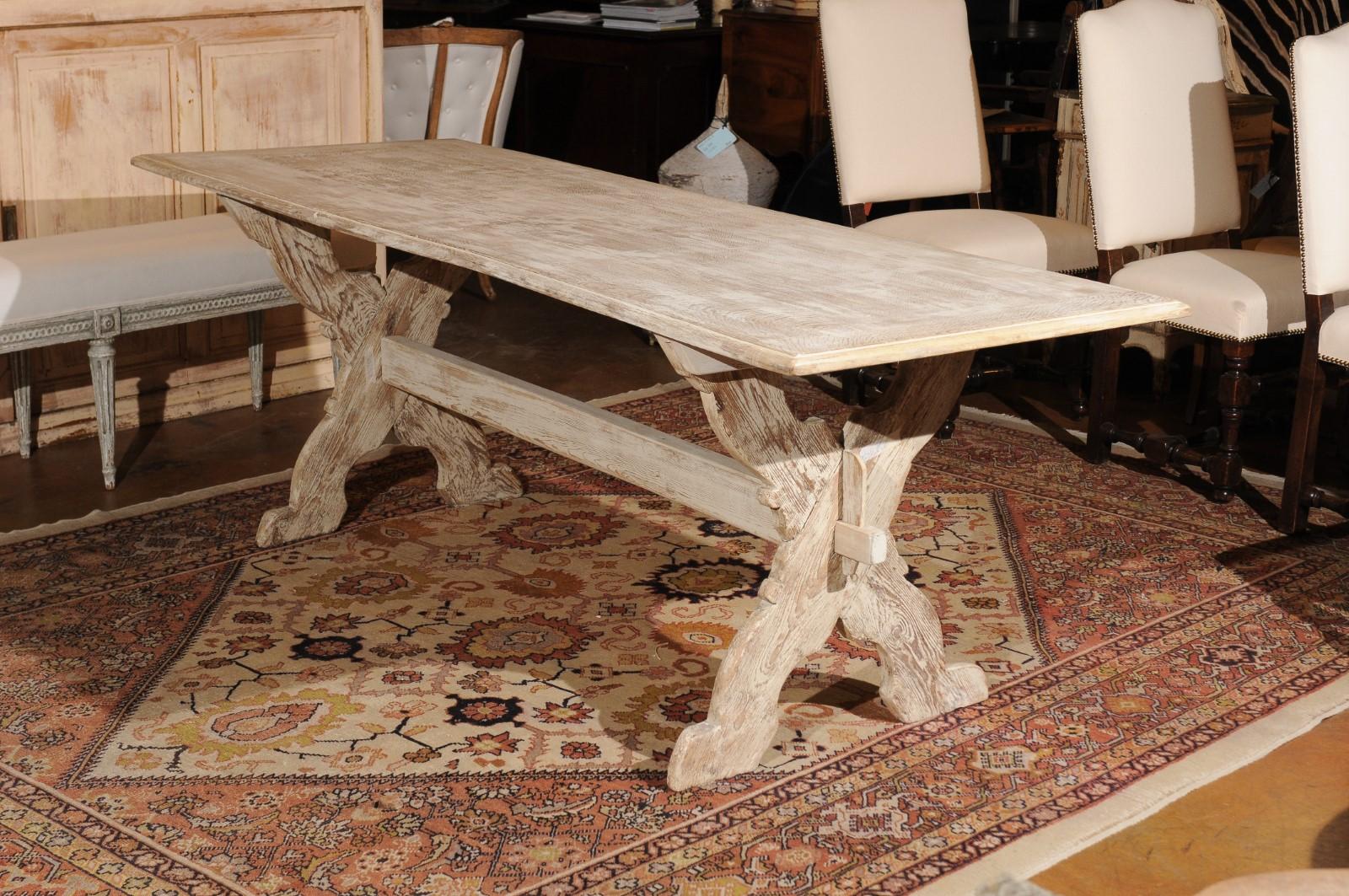 A Swedish painted trestle farm table from the late 19th century, with X-form base and distressed finish. Born in Sweden during the last decade of the 19th century, this charming farm table features a rectangular top sitting above a trestle base made