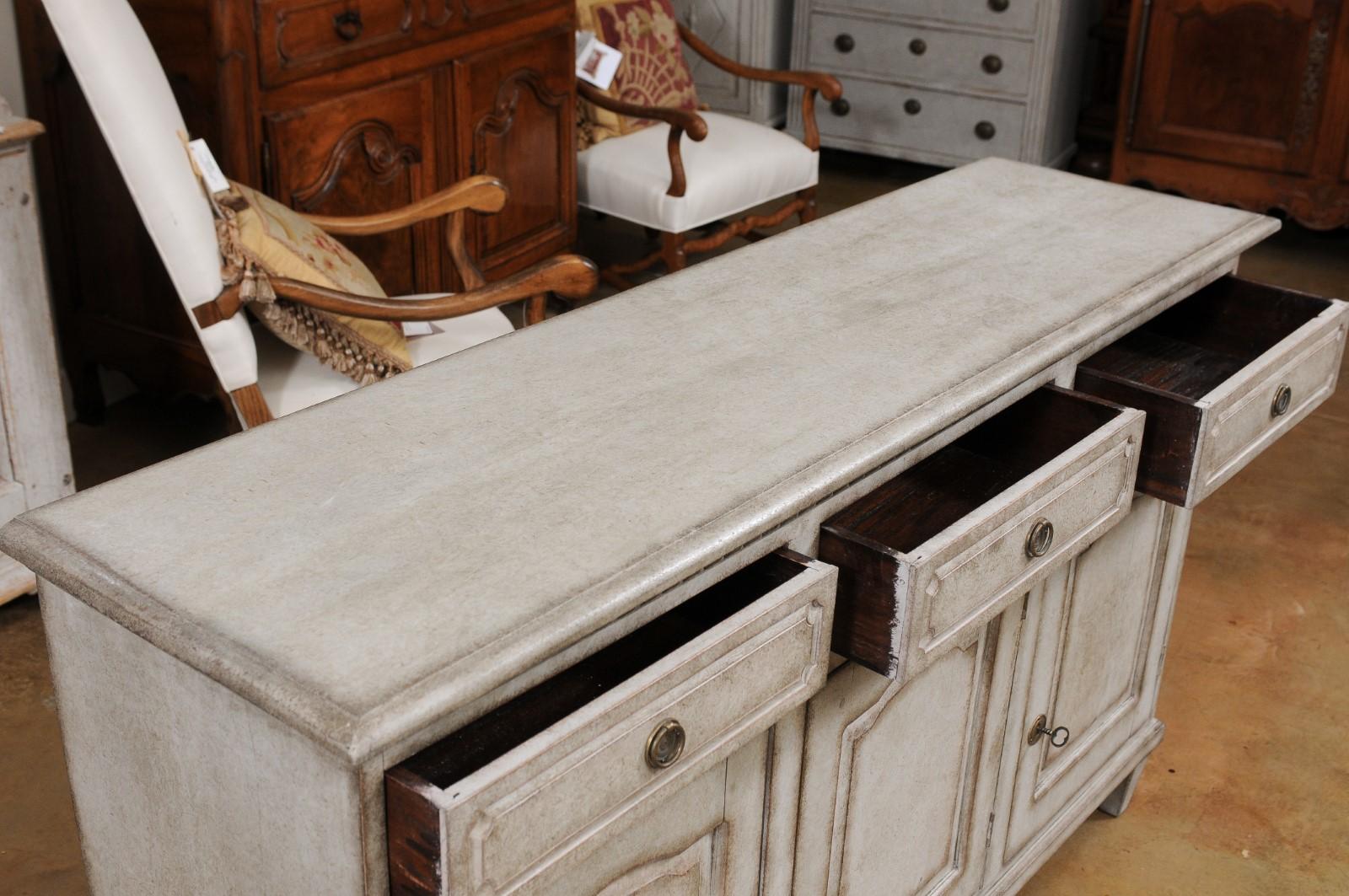 A Swedish painted wood sideboard from the late 19th century, with three drawers over three doors. Created in Sweden during the last decade of the 19th century, this painted sideboard features a rectangular top sitting above a carved molding. The