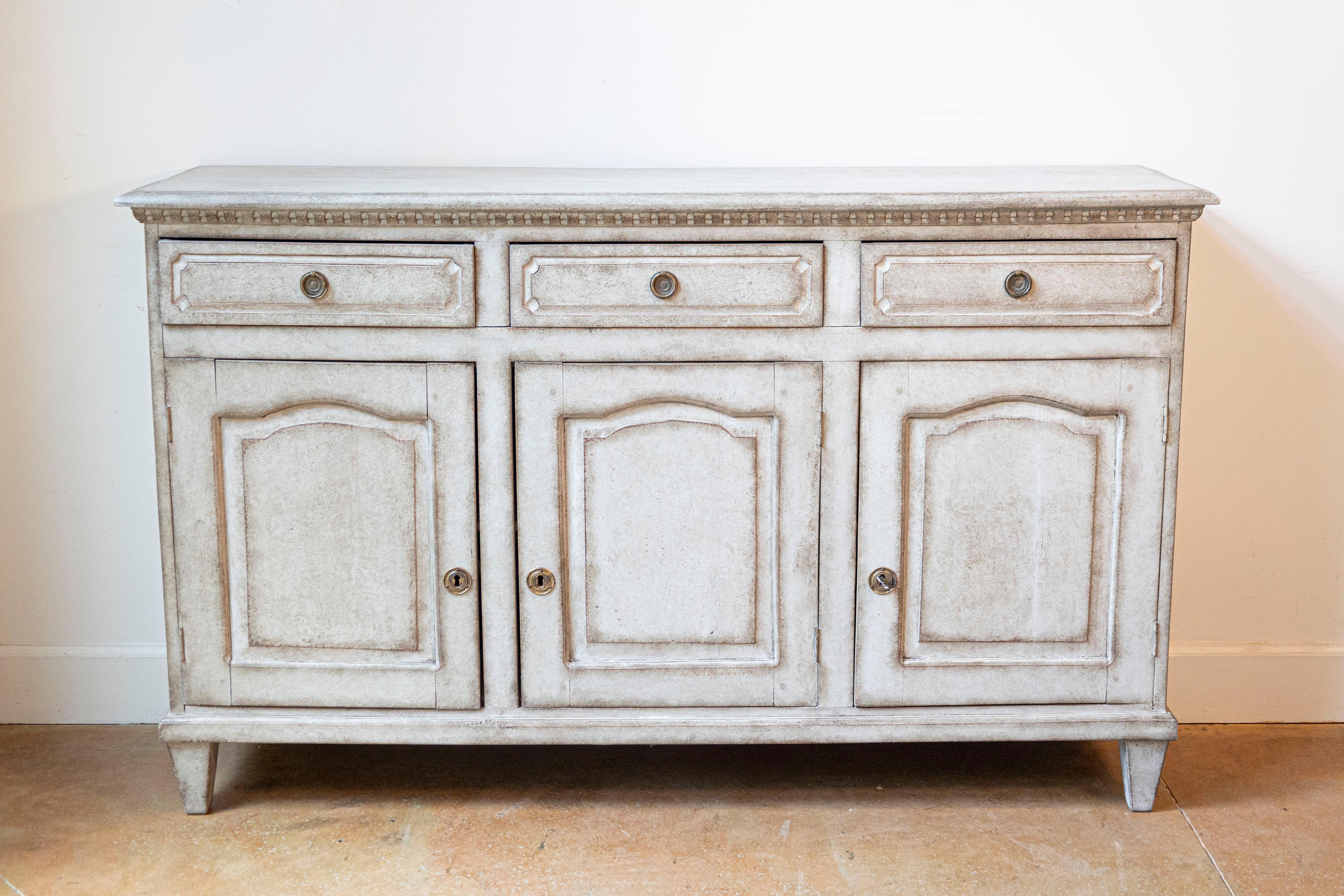 A Swedish painted wood sideboard from the late 19th century, with three drawers over three doors. Created in Sweden during the last decade of the 19th century, this painted sideboard features a rectangular top sitting above a carved molding. The