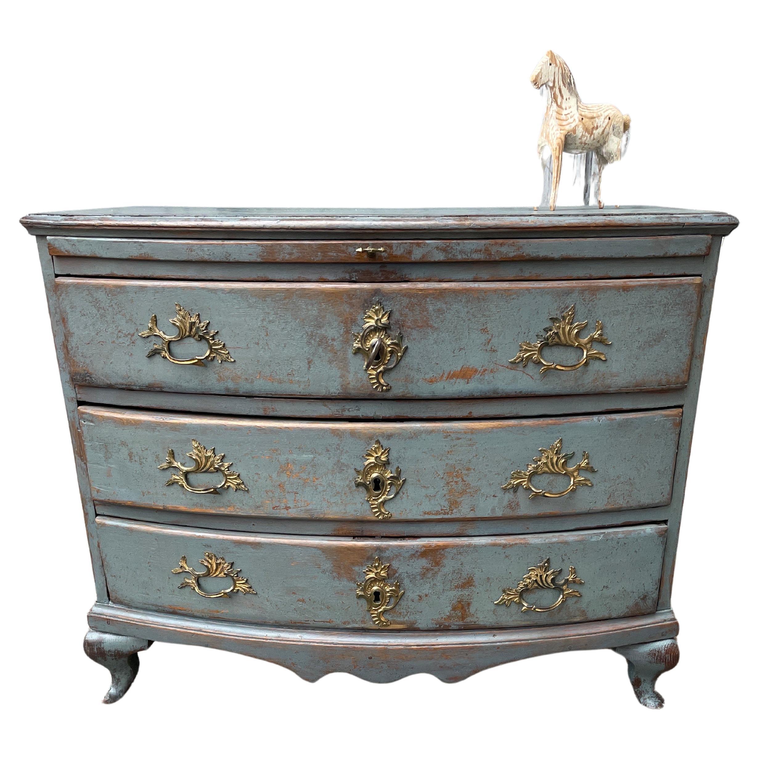 An exquisite 18th Century baroque 3 drawer chest. This blue painted three-drawer chest features a bow front, thick wood top with pull out shelf and scalloping on the front. The three drawers are adorned with their original baroque handles and
