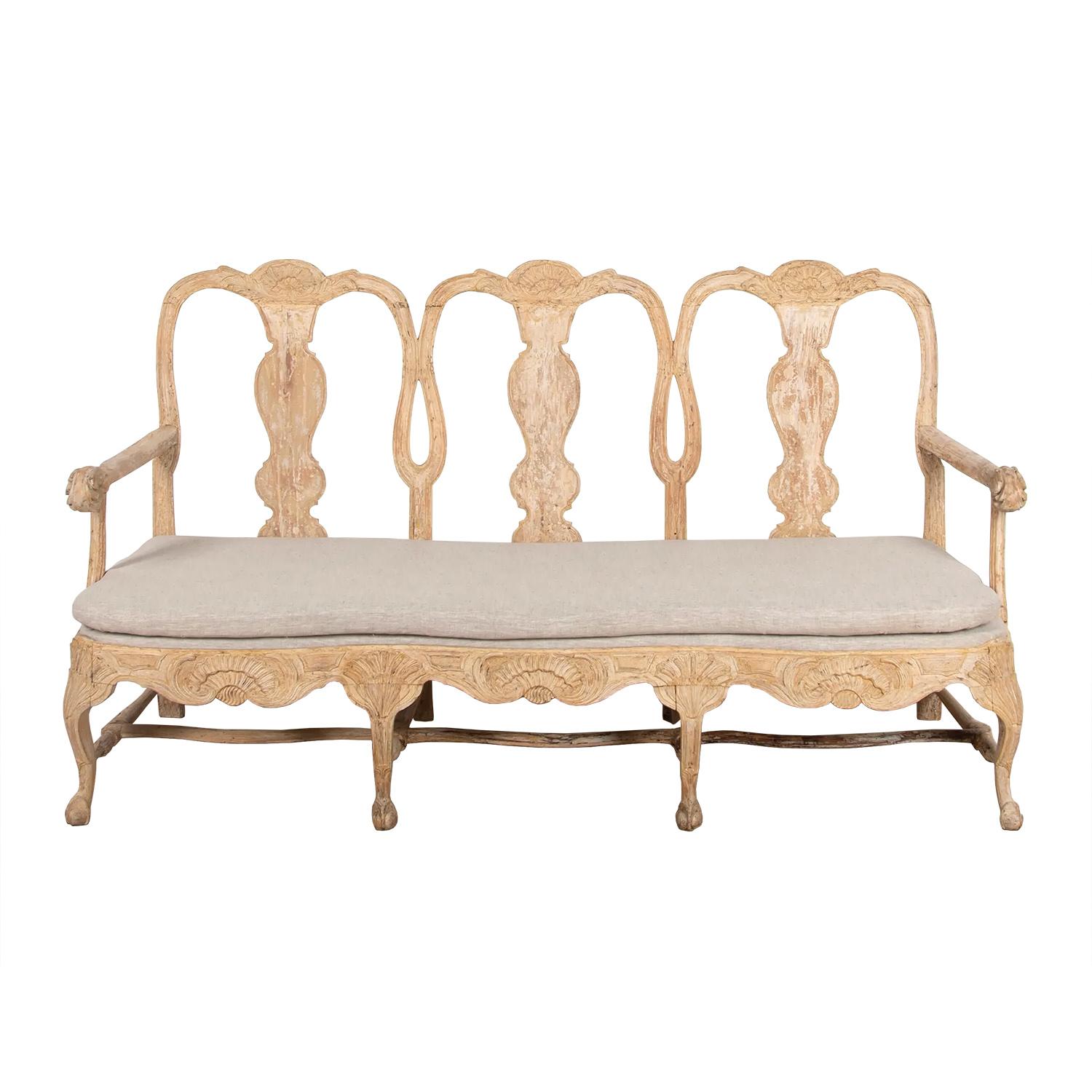 18th century Swedish Rococo sofa that has been dry scraped to original paint. This piece features decorative carved detailing, with legs tapering to ball and claw feet. The sofa has been reupholstered in linen. Lindome, Sweden.