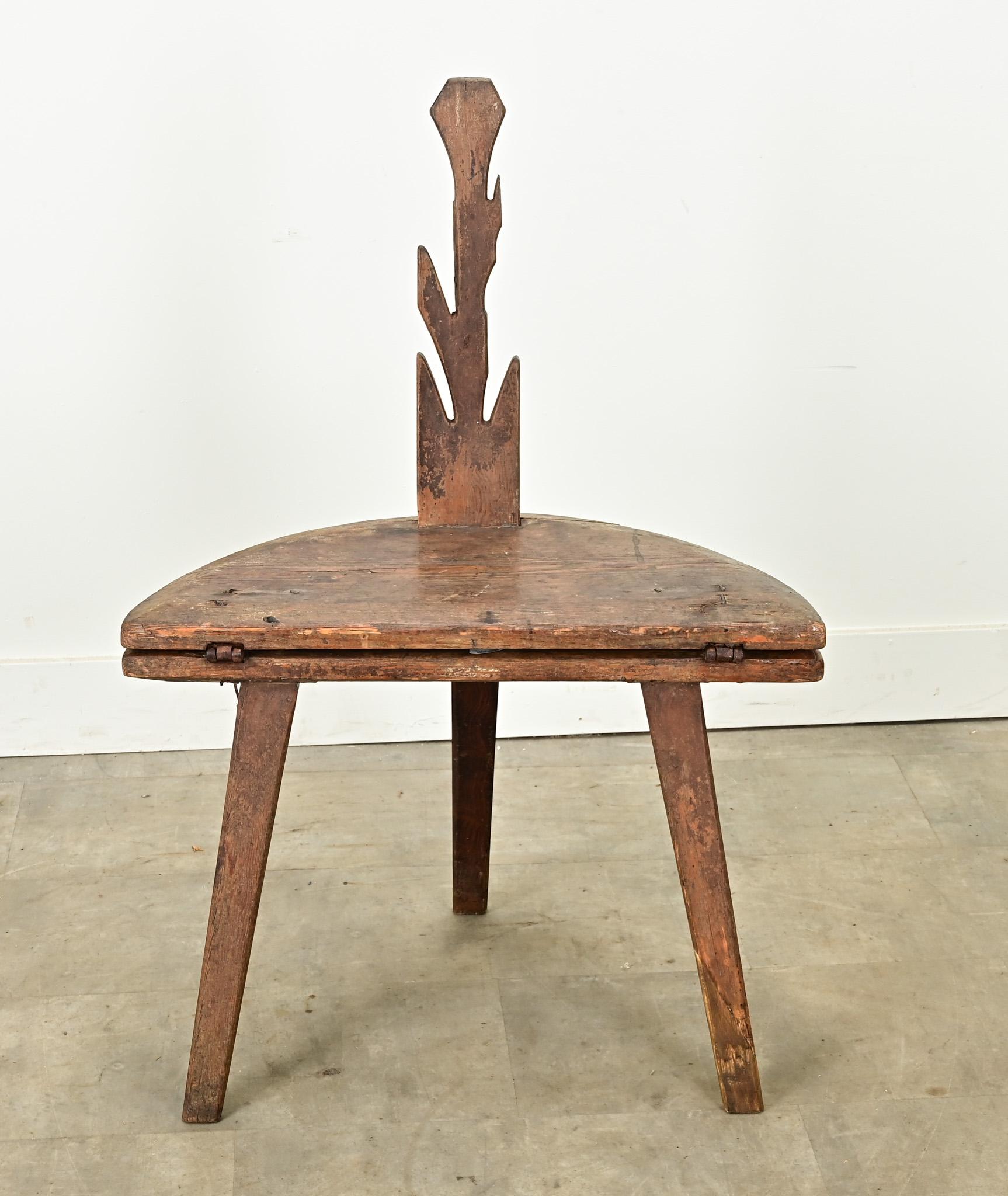 A solid pine chair-table from the Netherlands made in the 1800’s. This functional antique is a chair with a stylised back that converts into a table by use of hand forged iron hinges. This allows the chair’s back to fold down and form the table’s