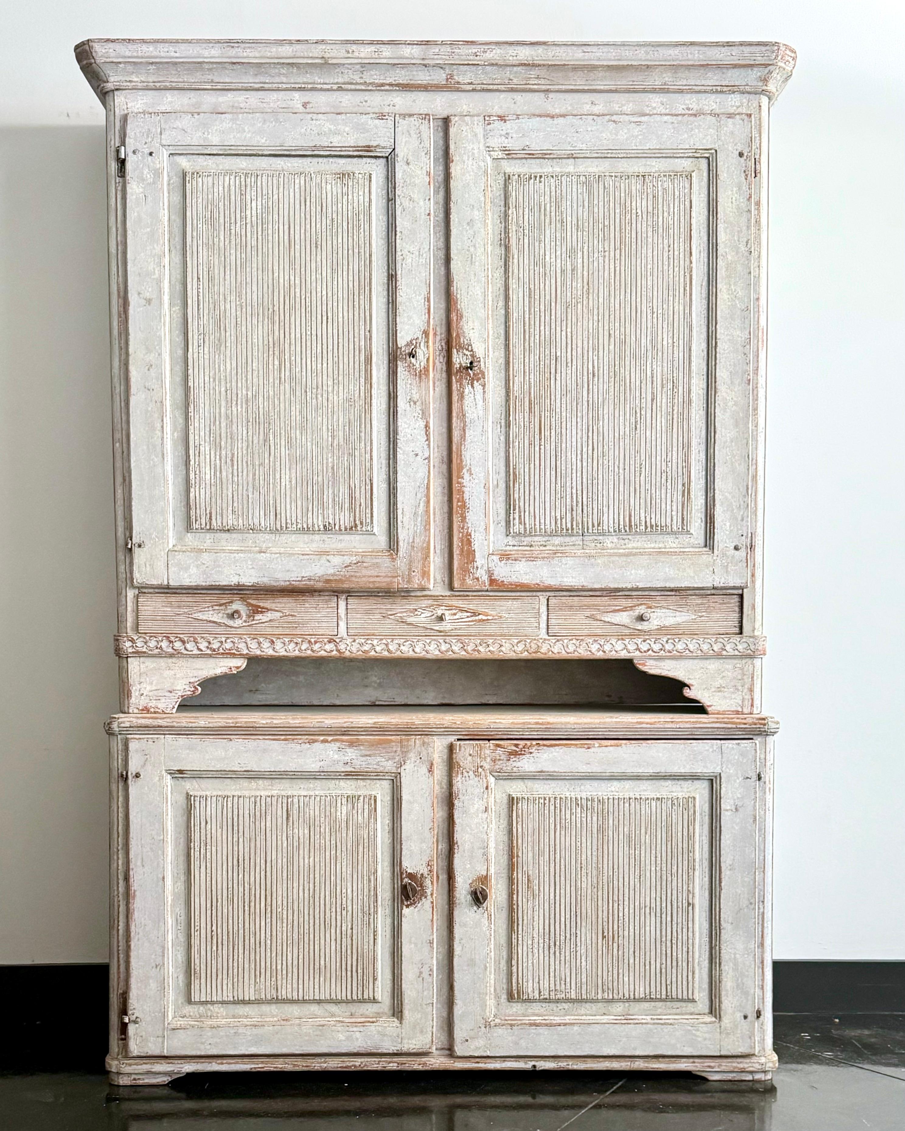 Large 18th century Swedish Gustavian period two-part cabinet/cupboard in scraped finish with remnant of the original paint. 
The upper cabinet with two reeded, paneled doors open several divided selves and one spoon slot self-
above three smaller