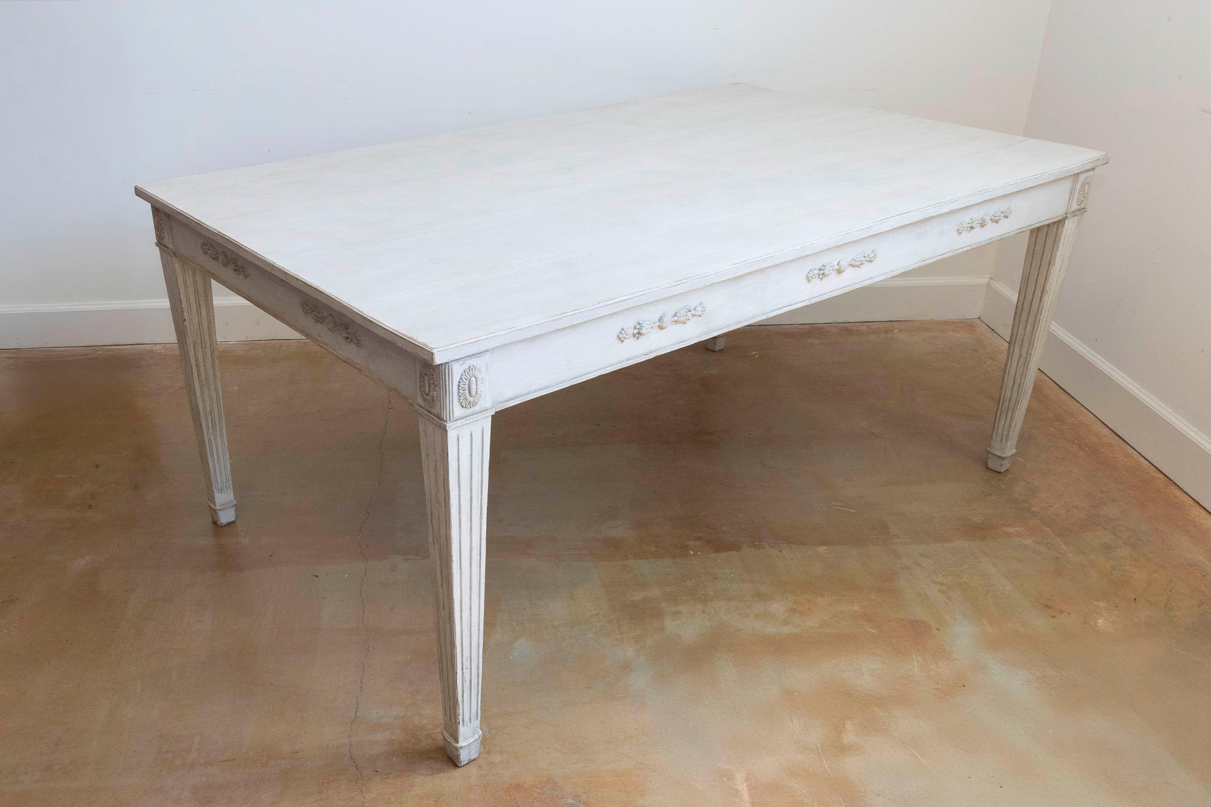 A Swedish Gustavian style painted wood dining table from the early 20th century with carved apron (measuring 25.25
