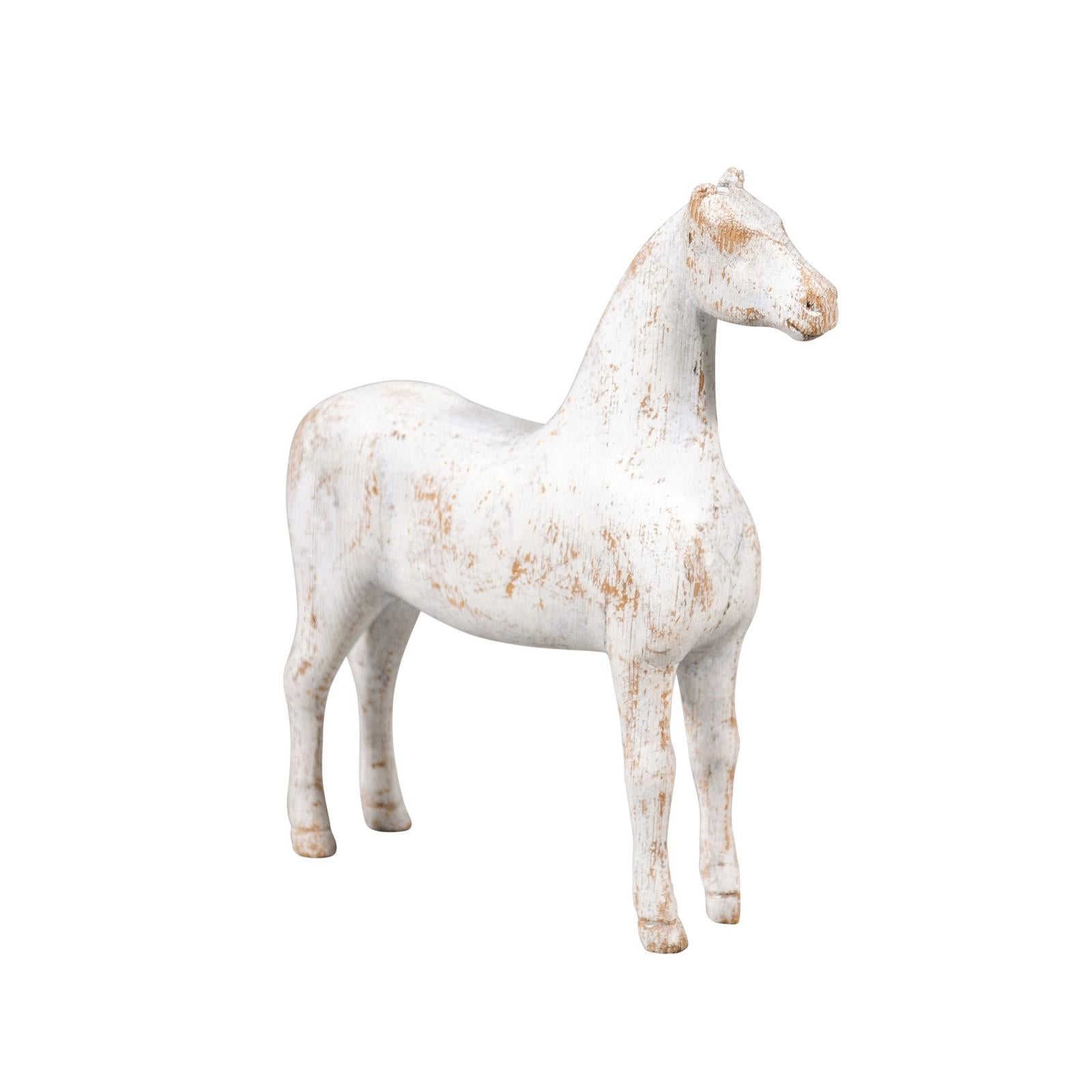 A small Swedish carved wooden horse sculpture from the early 20th century with distressed patina. Created in Sweden during the early years of the 20th century, this petite sculpture charms us with its rough treatment and weathered appearance.