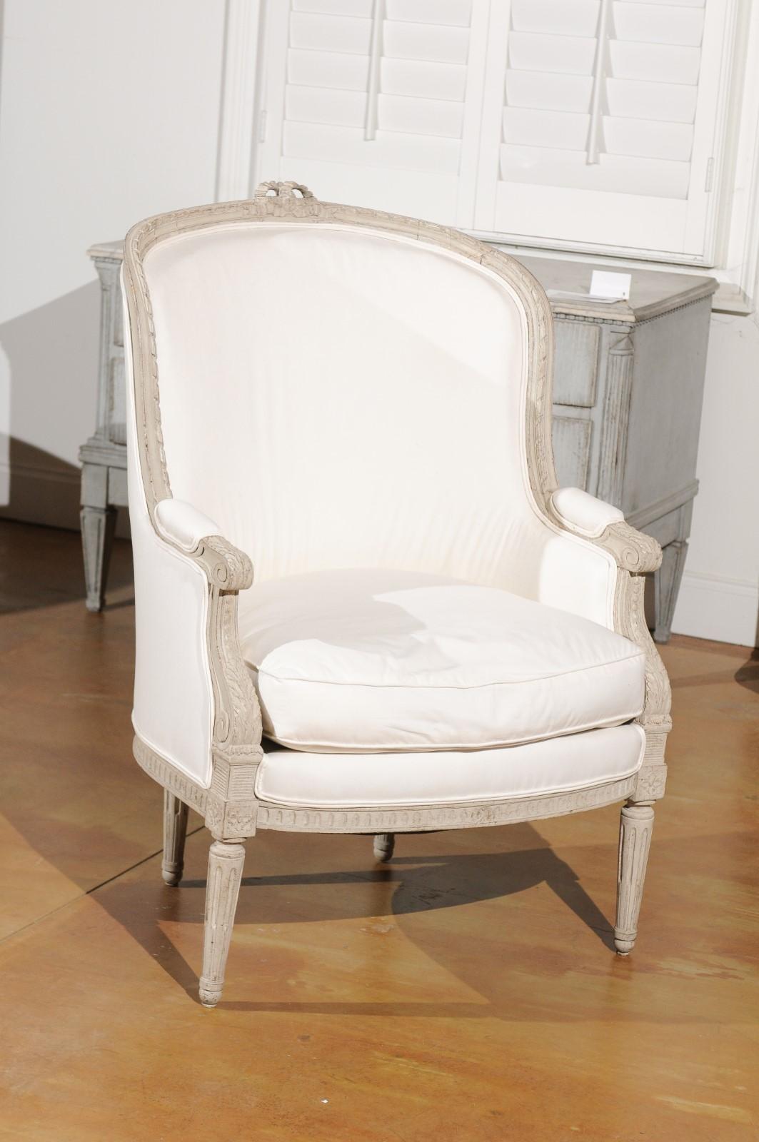 A Swedish neoclassical style painted wood barrel back bergère chair from the early 20th century, with carved bow, fluted legs and new upholstery. Born in Sweden during the early years of the 20th century, this exquisite barrel back chair presents