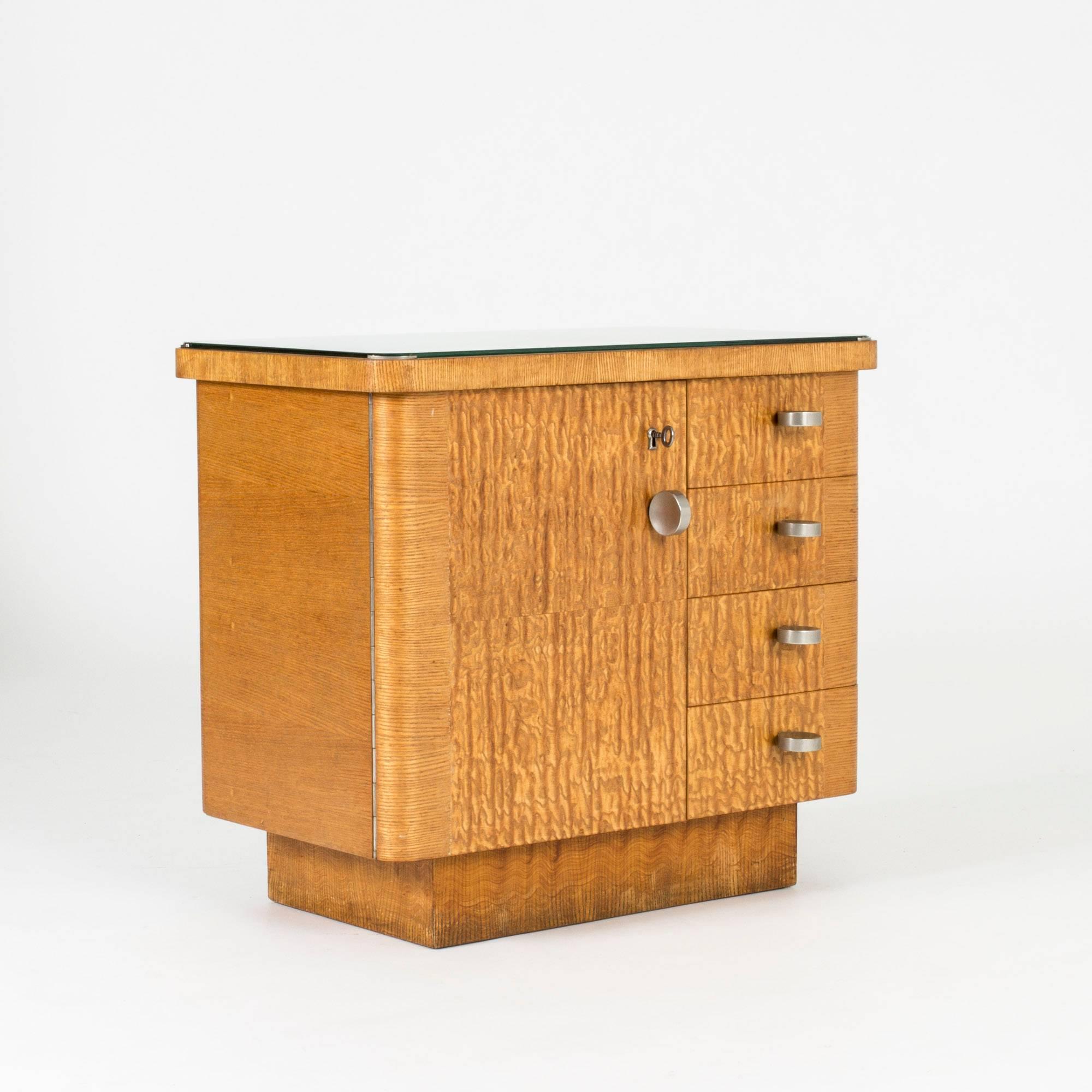 Sophisticated functionalist chest of drawers, made in Sweden in the 1930s. The clean-cut design with root veneer has great details in the well-made metal rims holding the glass in place, brushed-steel handles and hinges running along the entire