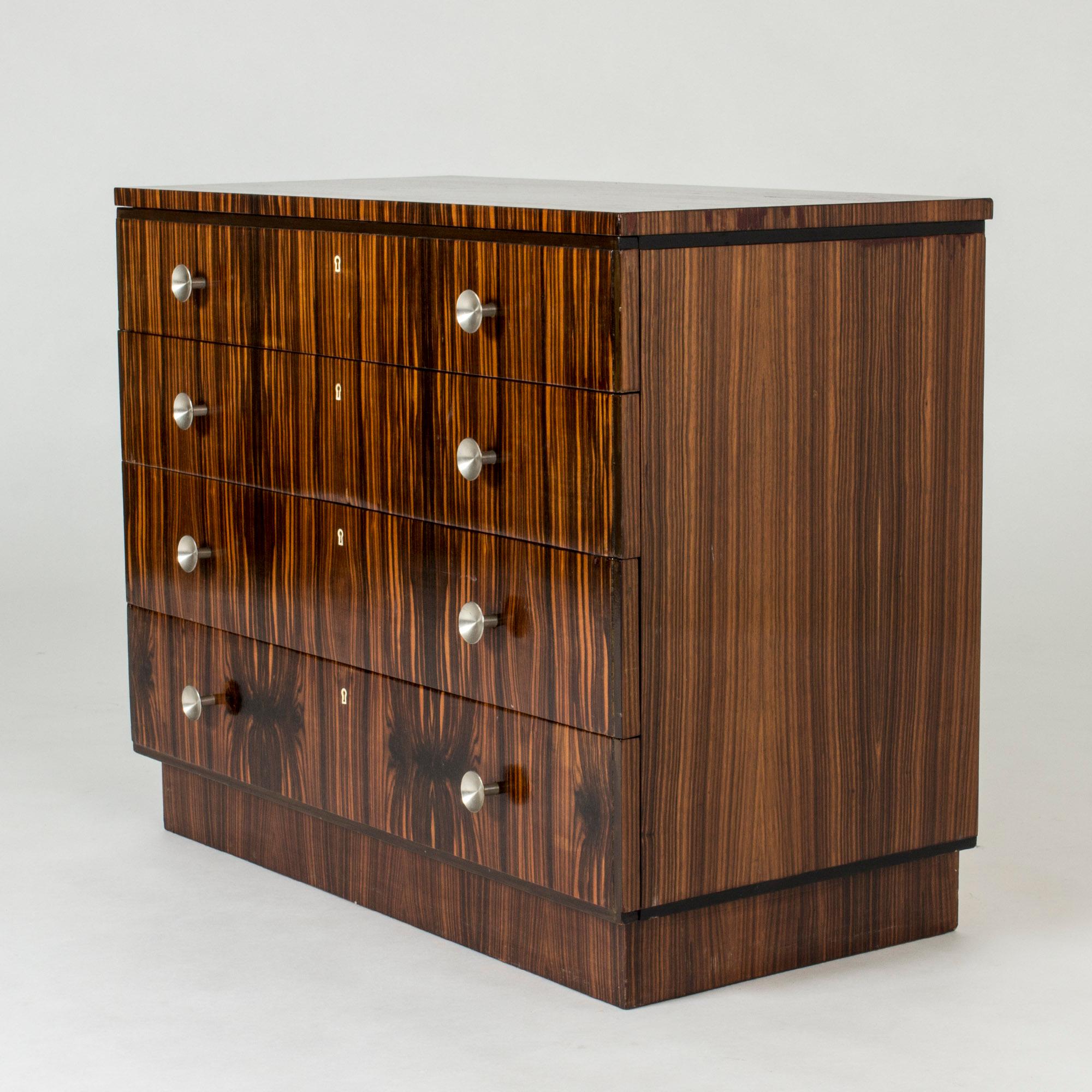 Swedish functionalist chest of drawers in striking zebrano veneer. Cool round brushed steel handles contrast against the lively wood.