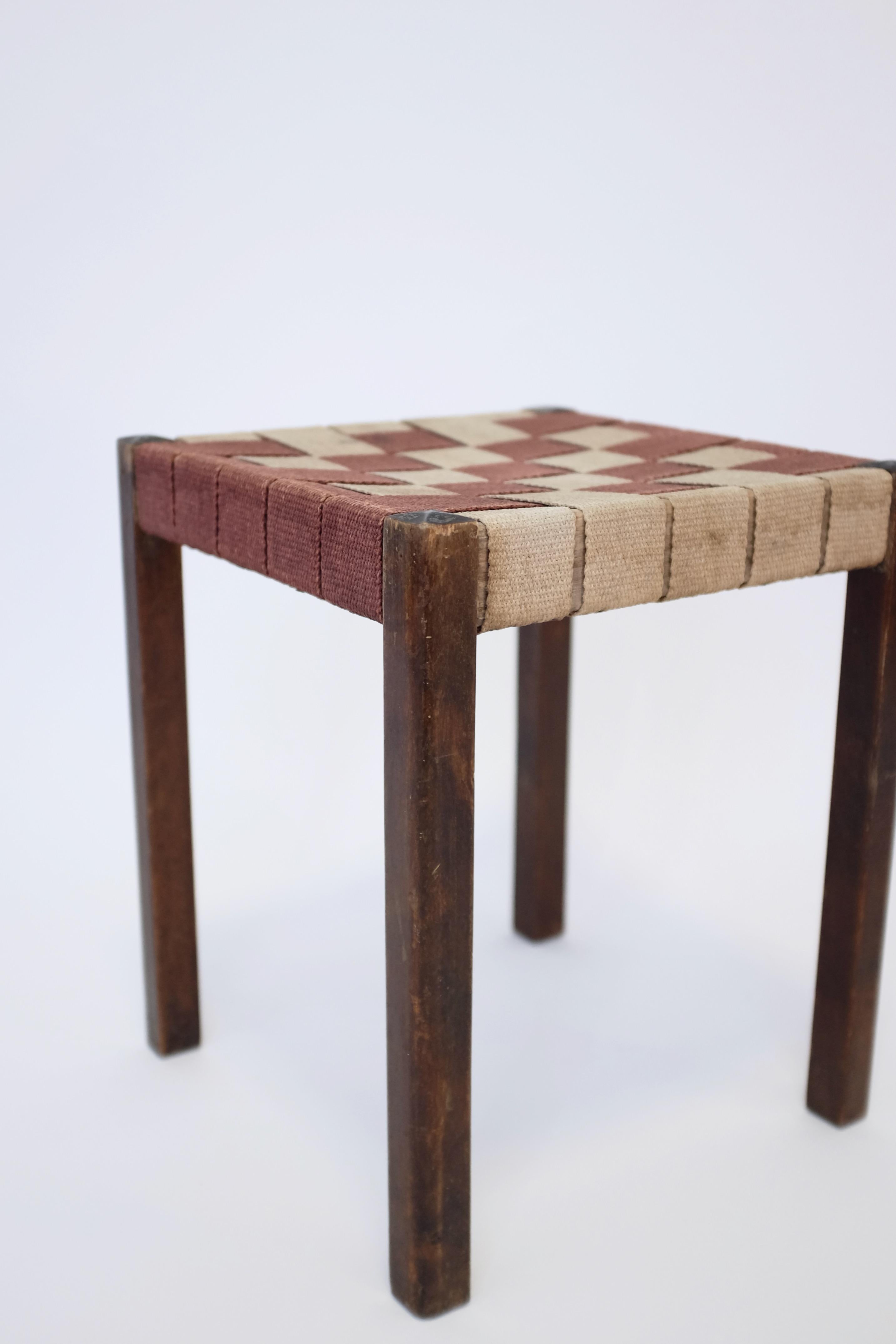 Charming 1930's webbed stool by Axel Larsson for Bodafors, a Swedish furniture company. Made of stained birch with a red-brown and beige canvas webbing it is typical for the kind of practical and modern looking furniture that was produced during