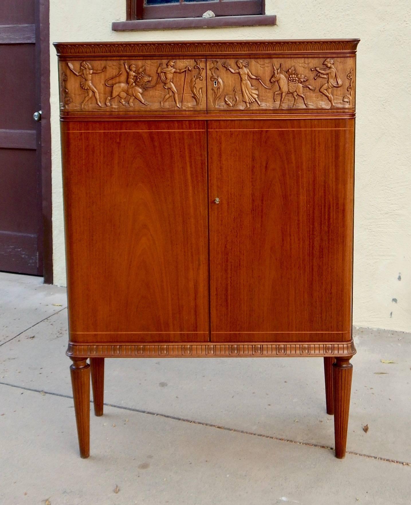 Swedish, 1940s moderne storage cabinet by Eugene Höglund, Vetlanda, Sweden, circa 1940. Doors in open grained mahogany Upper cabinet in stained solid birch with high relief carving. There are four drawers behind the swinging relief doors. There are