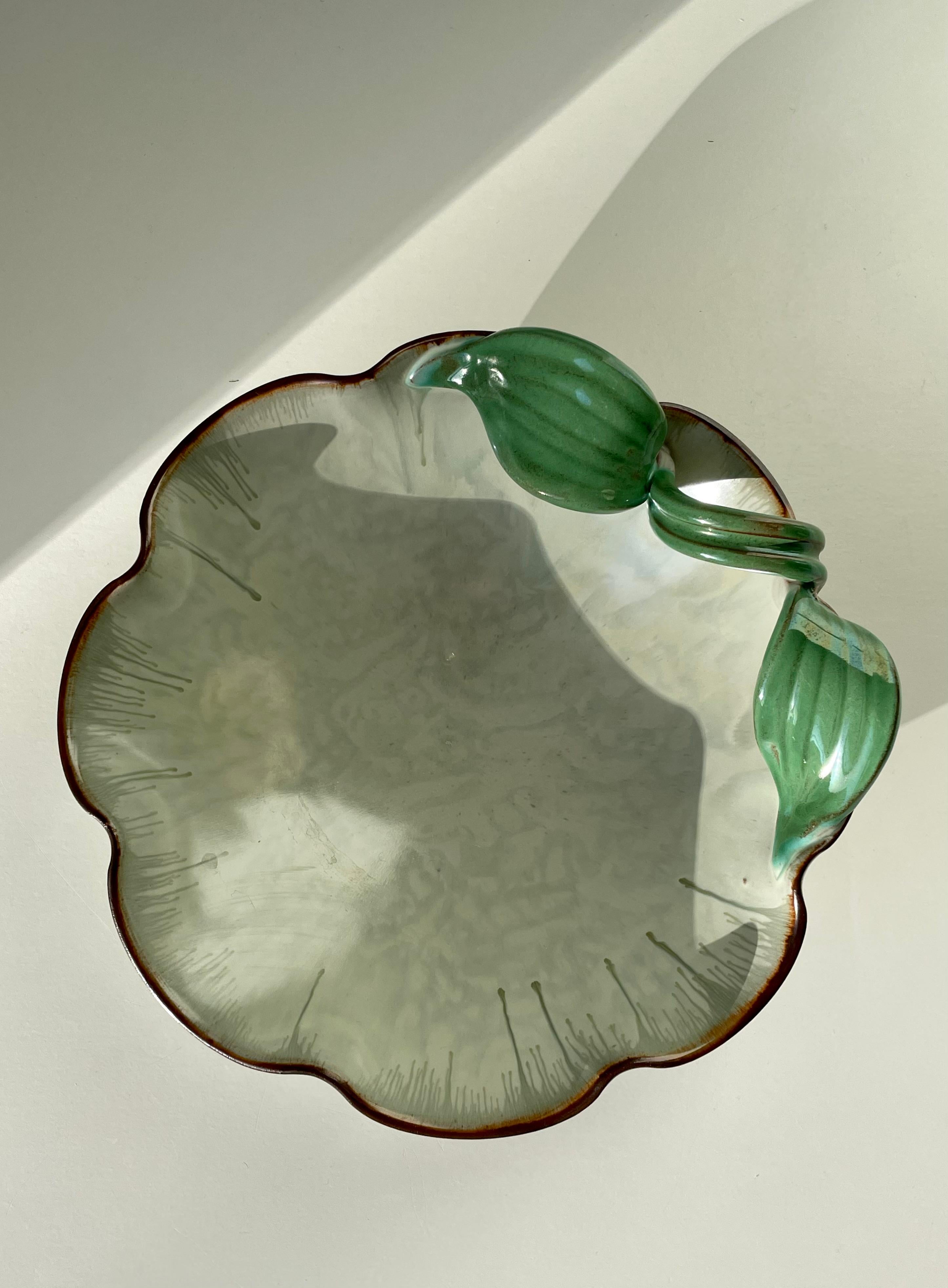 Stunning handmade Swedish 1940s Art Nouveau decorative vide poche bowl. Green leaves organically pouring over one side of the light green piece with thin decorative lines of running glaze on all sides. Stamped under base. Beautiful vintage