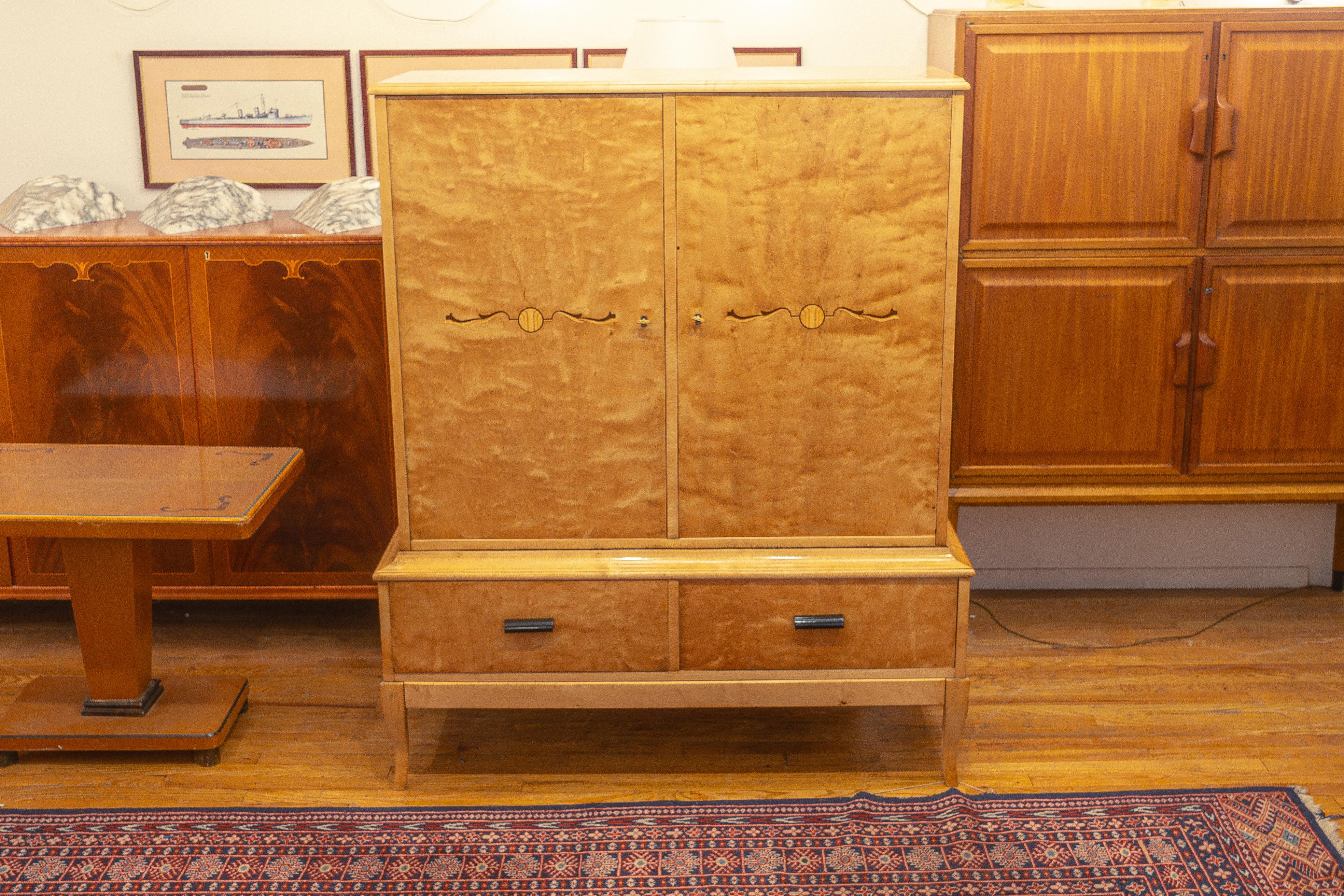 Constructed in the straightforward style of the start of the mid-modern period.  The Nordic birch veneers radiate warmth and add a natural element to the case itself.  Both doors are inlaid as was the fashion of the preceding Deco period.  