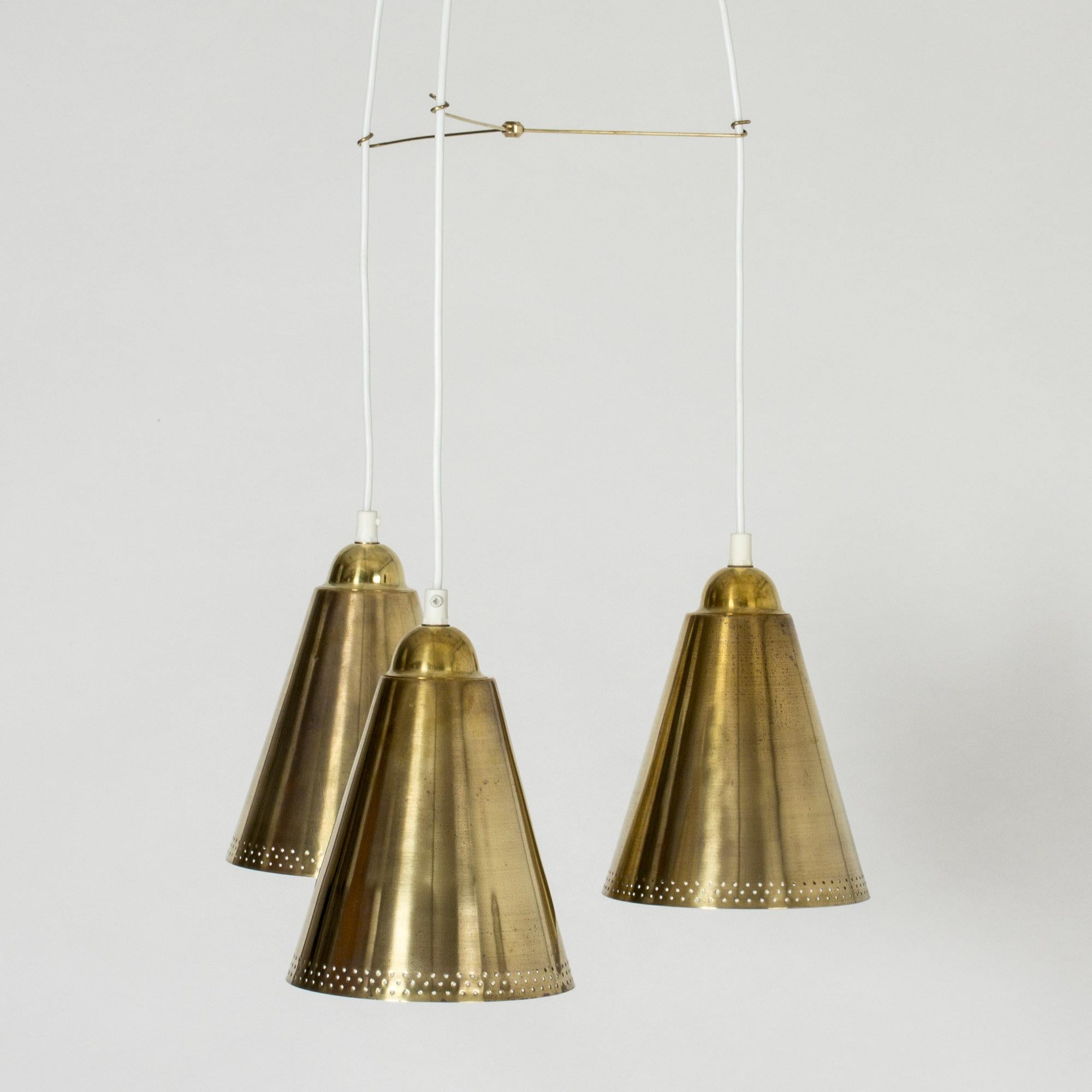 Beautiful brass pendant lamp with three shades, made in Sweden in the 1950s. The shades are perforated with small holes along the lower edges. The cords are separated by a slender brass arms that are connected in the middle. Very nicely made with