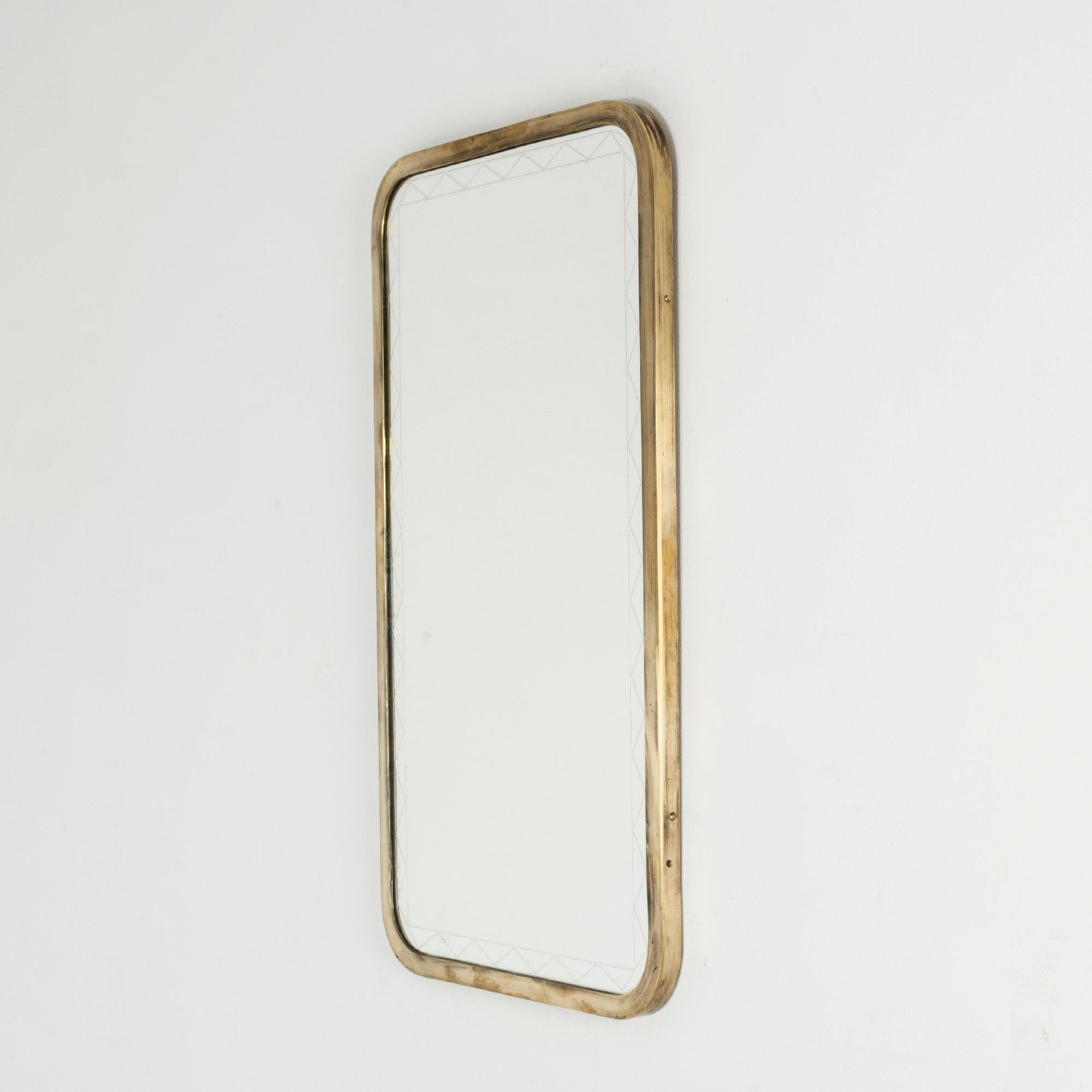 Beautiful Swedish 1950s wall mirror with a brass frame with rounded corners. Graphic pattern etched into the glass around the frame.