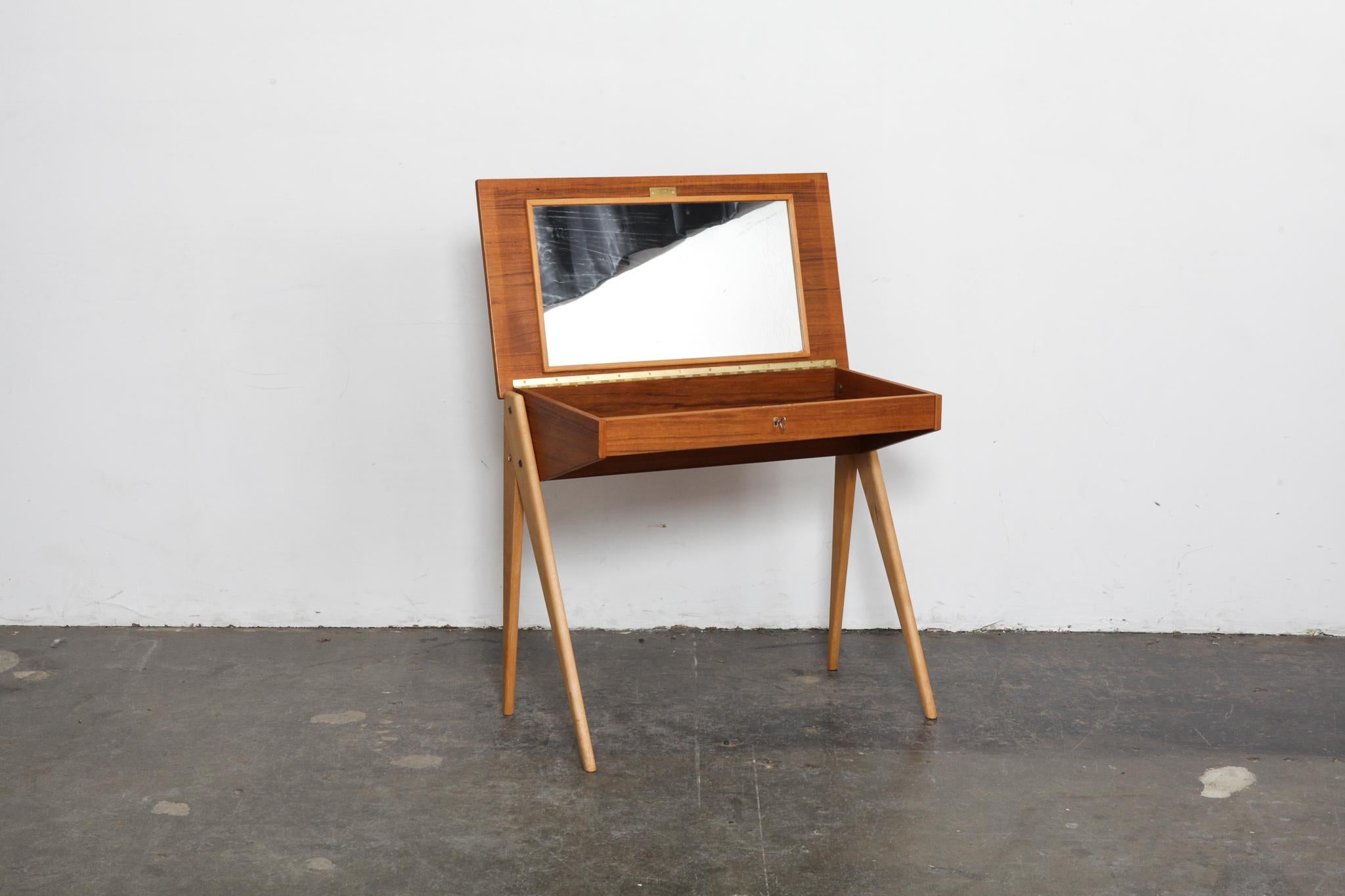 Swedish 1950s teak desk or vanity with swing opening top that locks, interior mirror and solid beech 'A' frame legs. Newly refinished in a natural teak oil matte finish.