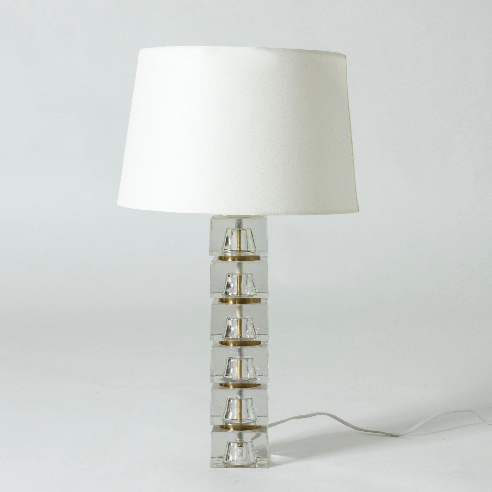 Cool Swedish 1960s crystal table lamp where the base is made from translucent blocks. A slender brass pipe concealing the wiring runs through the middle of the base, creating a cool visual effect. The sections between the blocks are painted gold.