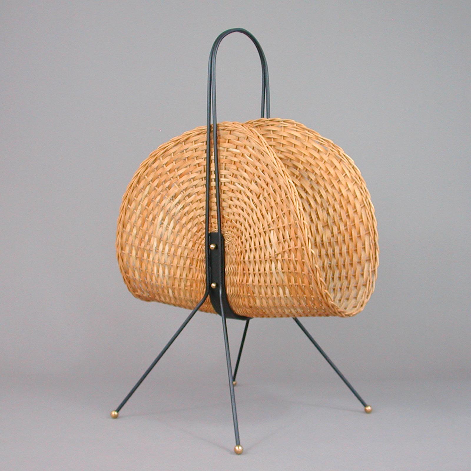 This unusual elegant rattan magazine rack was designed and manufactured in Sweden in the 1960s. It features a streamline woven rattan basket, a black enameled metal frame and brass details.
