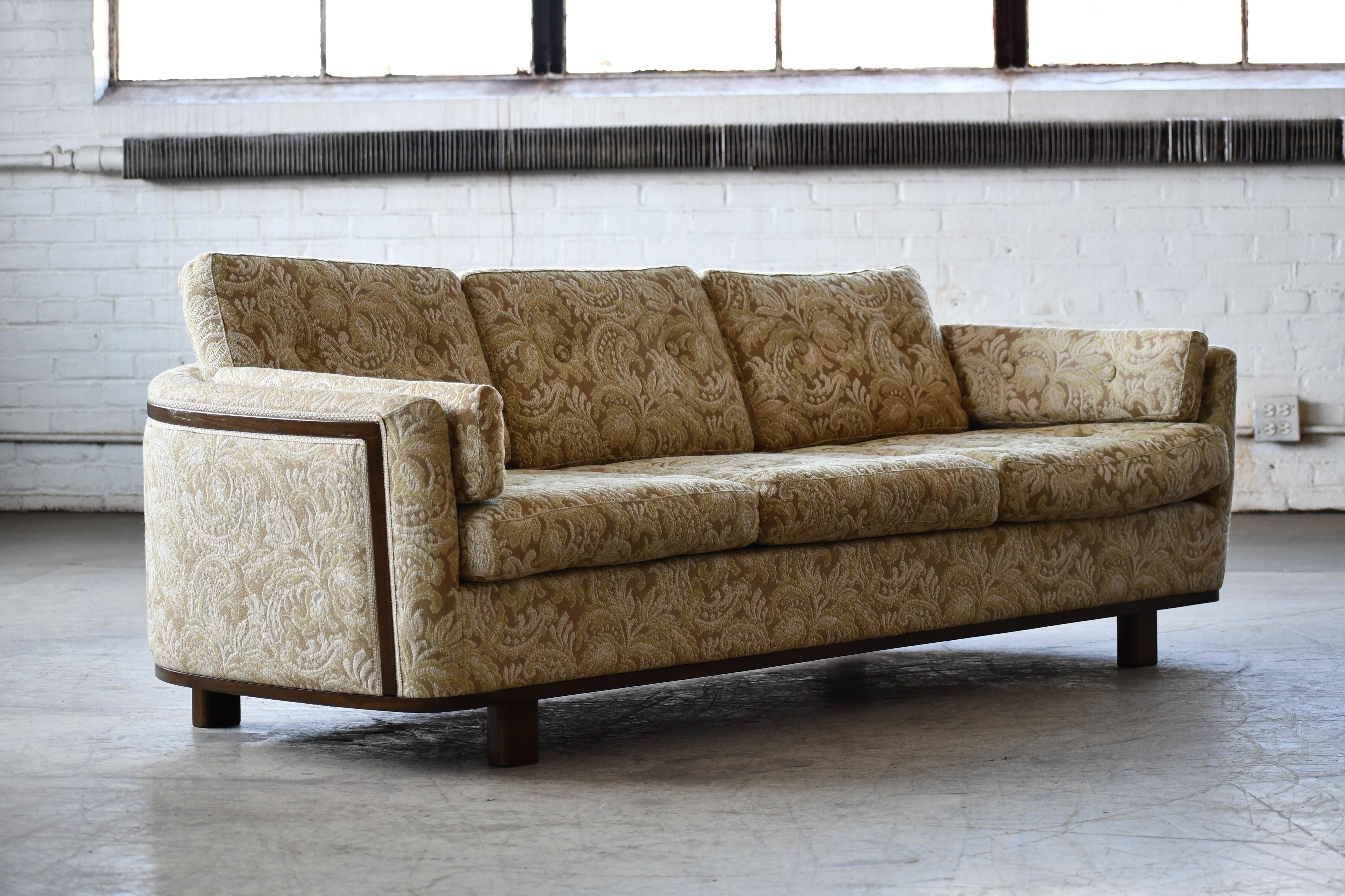 Swedish midcentury modern upholstered sofa with walnut colored wood accents and base made by Holm's Fabriker AB. The wooden accents are built in to the sofa according to Swedish tradition and adds an upscale flair and elegance. Rounded organic