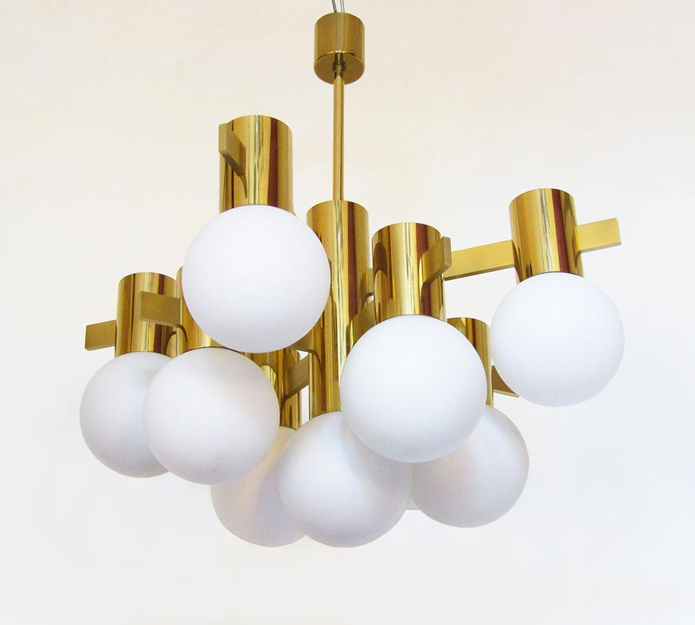 A geometric 1970s brass chandelier with cased glass orb shades by Swedish designer Hans Agne Jakobsson.

It has nine individual lights on three tiers supported by eight brushed brass arms.

The shades emit a warm, diffused light.

This