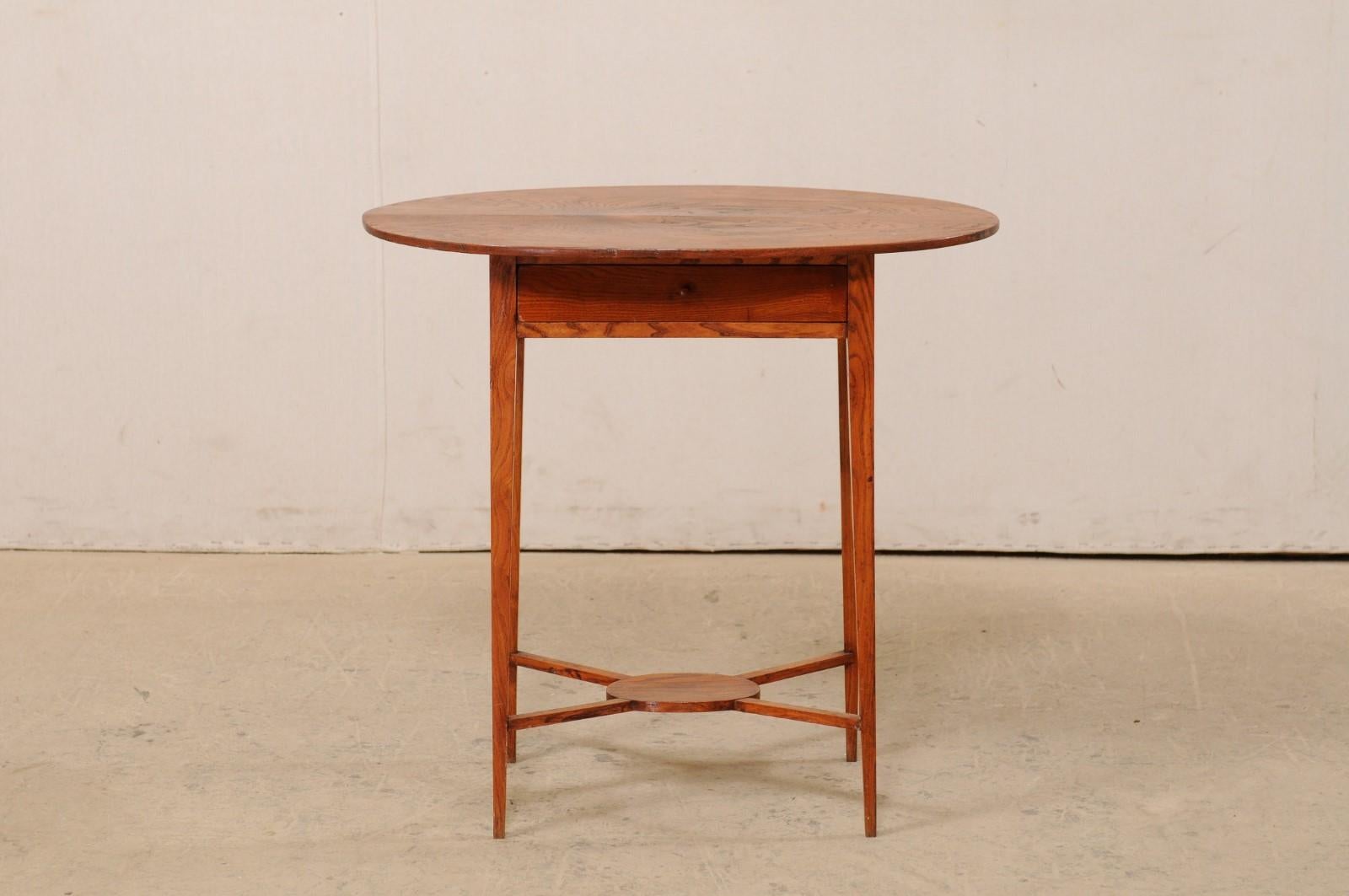 A Swedish oval top, elm wood, side table from the 19th century. This antique table from Sweden, created from Elm wood, features an oval-shaped top, with a cleanly designed apron beneath which houses a single drawer (fitted with wood knob pull) at
