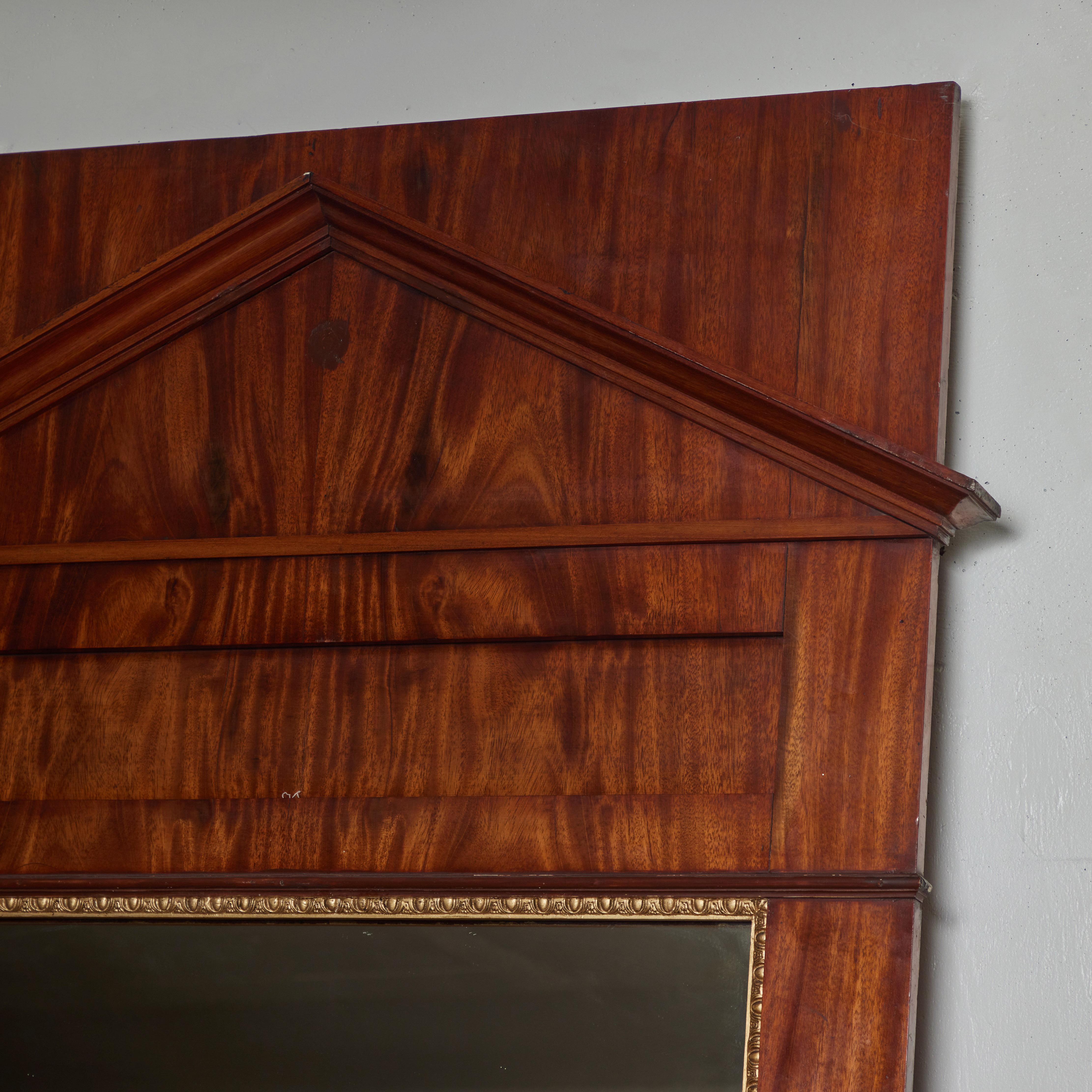 Questo grande specchio Swedish Empire presenta una cornice in mogano, caratterizzata da linee pulite e classiche e da una profonda tonalità miele. Il design emana un'eleganza senza tempo e un fascino architettonico che lo rendono un'aggiunta