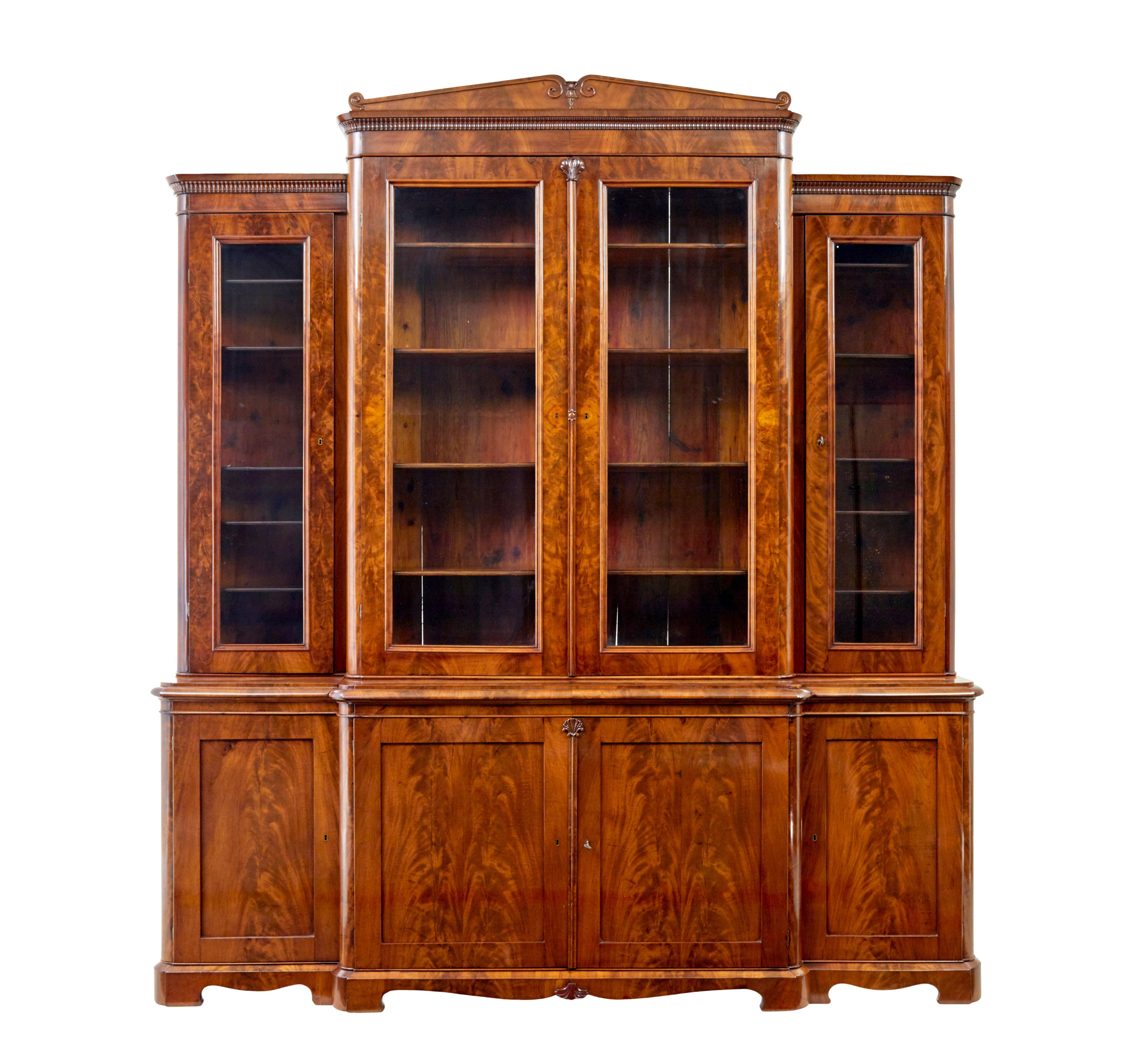 Early 19th century Scandinavian empire flame mahogany breakfront bookcase circa 1820.

Stunning bookcase of grand proportions veneered in golden flame mahogany.  Bookcase comprises of 7 sections which screw together to.  3 sections to the base, 3