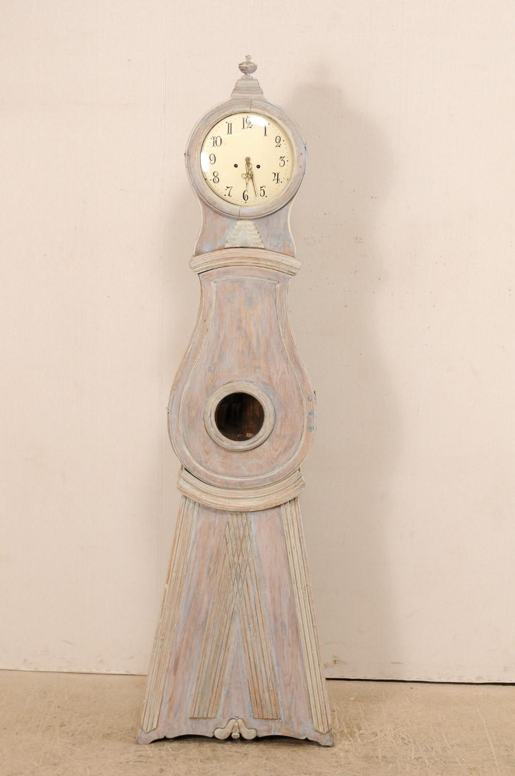 A 19th century Swedish grandfather clock. This Swedish clock features a round-shaped head which has been topped at crest with a carved finial, decorated neck at center, a raindrop shaped belly, with triangular bottom which has been carved in
