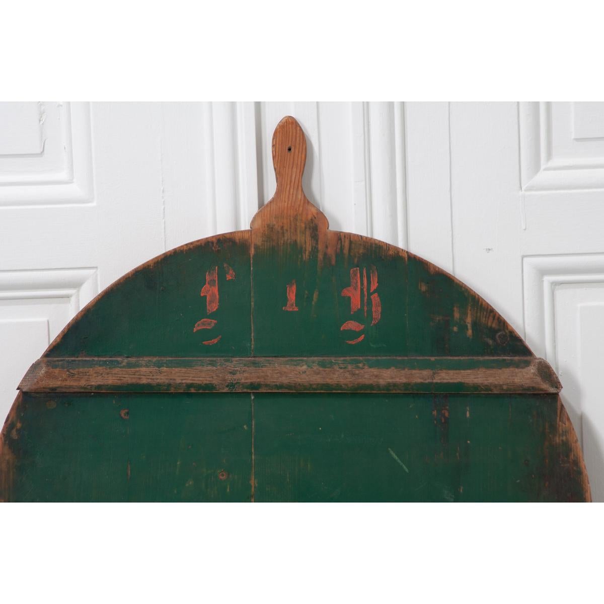 Charming, antique pine peel board, circa 1840. These boards were designed with one side painted to look attractive when not in use and unfinished on the other side when in use. This green board, with remnants of orange lettering, can be a