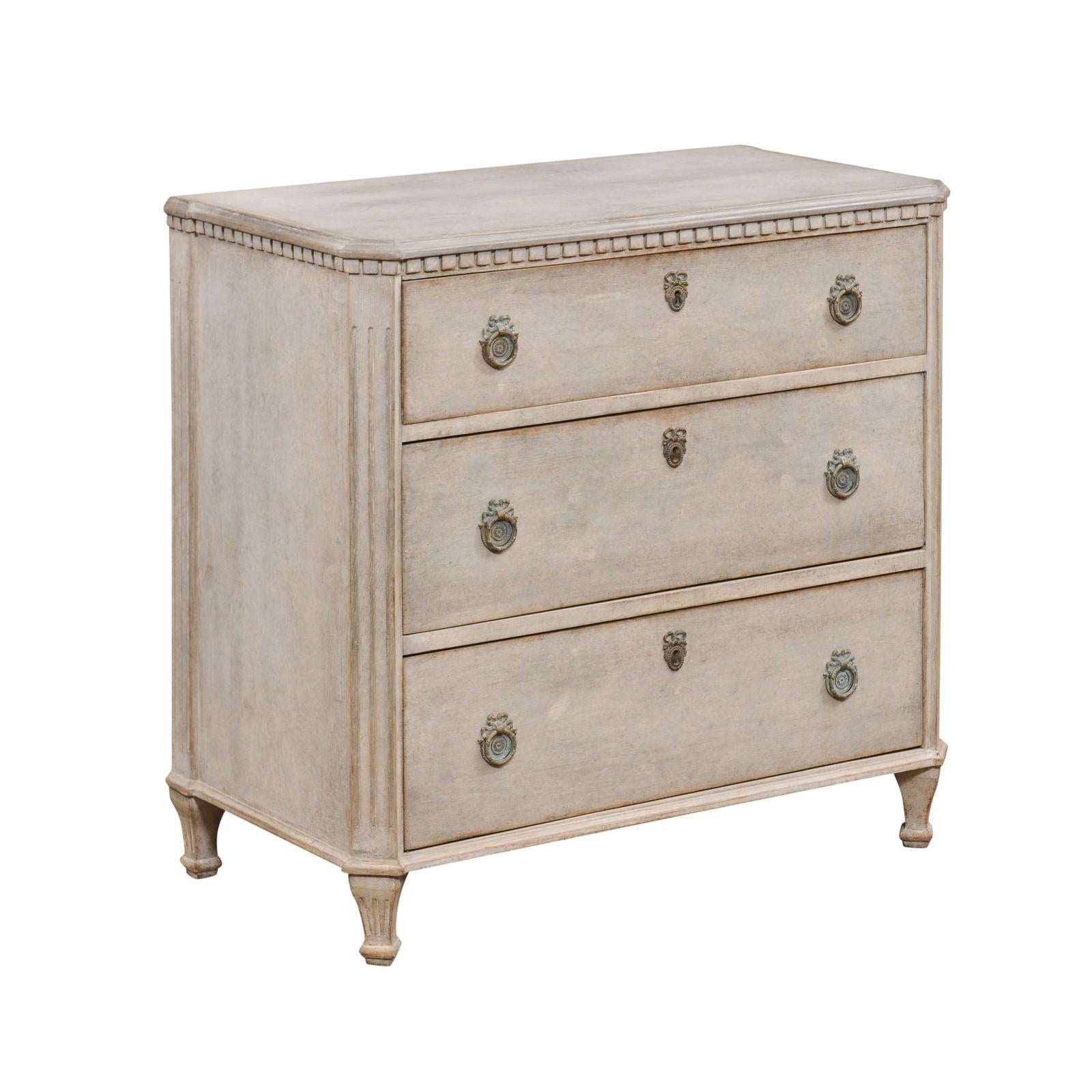 Swedish 19th Century Gustavian style three-drawer painted wood chest with carved dentil molding and fluted side posts. Immerse yourself in the charm of Swedish craftsmanship with this 19th Century Gustavian style chest of drawers. This piece