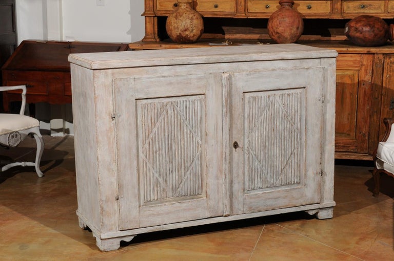 A Swedish Gustavian style sideboard from the 19th century, with diamond motifs and reeded accents. Created in Sweden during the 19th century, this painted sideboard features a rectangular top sitting above two doors, adorned with vertical diamonds