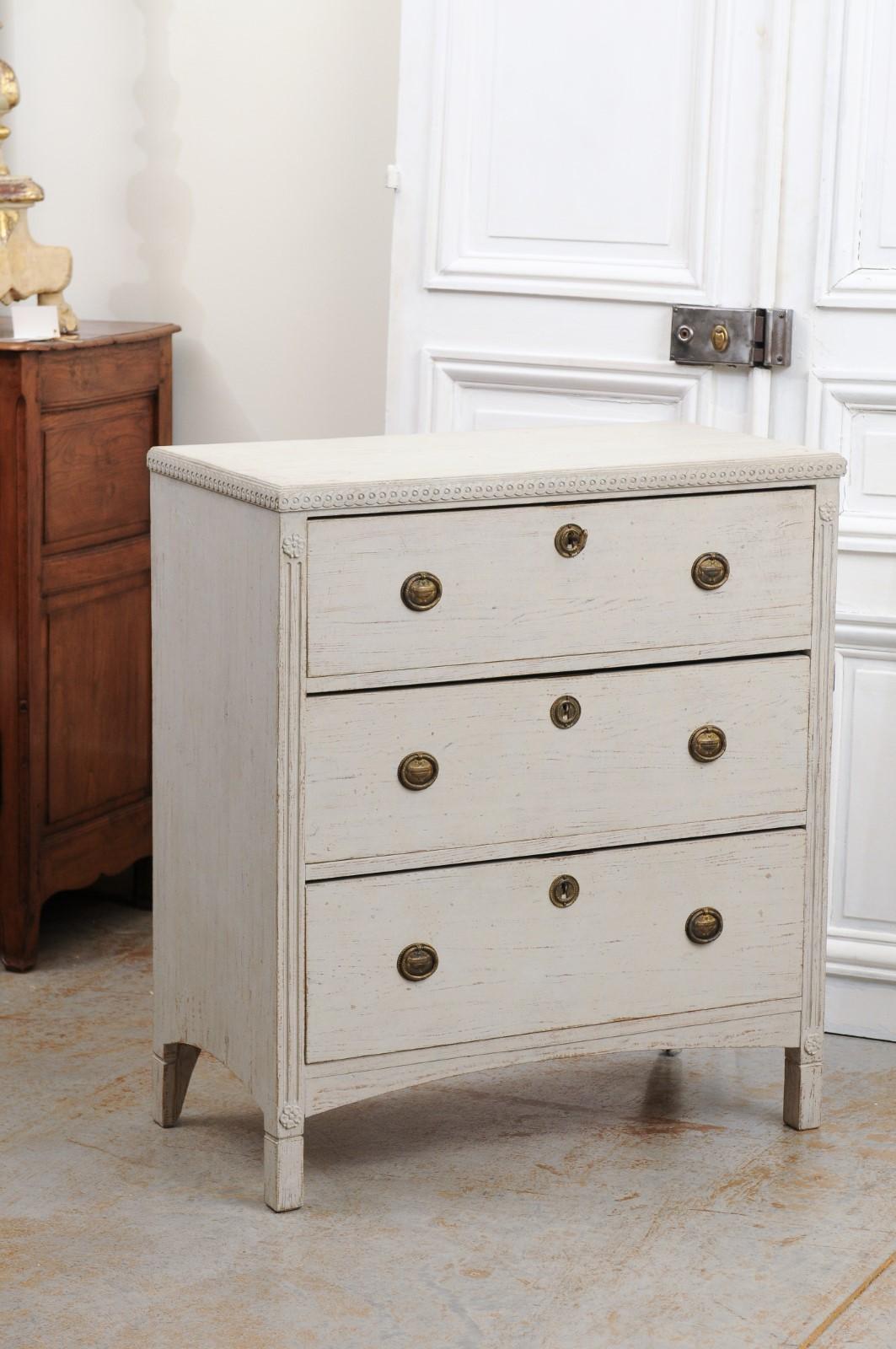 A Swedish Gustavian style painted wood chest from the 19th century, with three drawers, carved guilloche frieze and fluted accents. Created in Sweden during the 19th century, this Gustavian style painted chest features a rectangular top sitting
