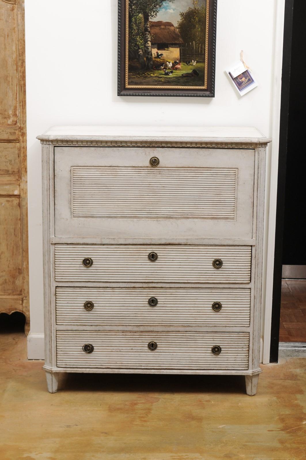 A Swedish Gustavian style painted wood drop-front secretary from the 19th century, with dentil molding, reeded accents and multiple drawers. Born in Sweden during the 19th century, this exquisite painted Gustavian style secretary features a