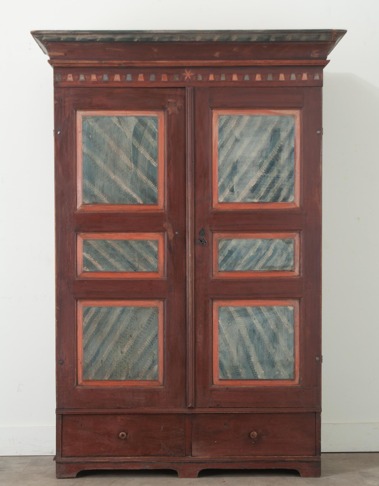 A Swedish Gustavian cabinet handmade in Halsingland during the 1700’s. This armoire is made of pine and has its original vibrant paint finish. The top features a sharply molded cornice atop a pair of paneled double doors over a pair of drawers. The