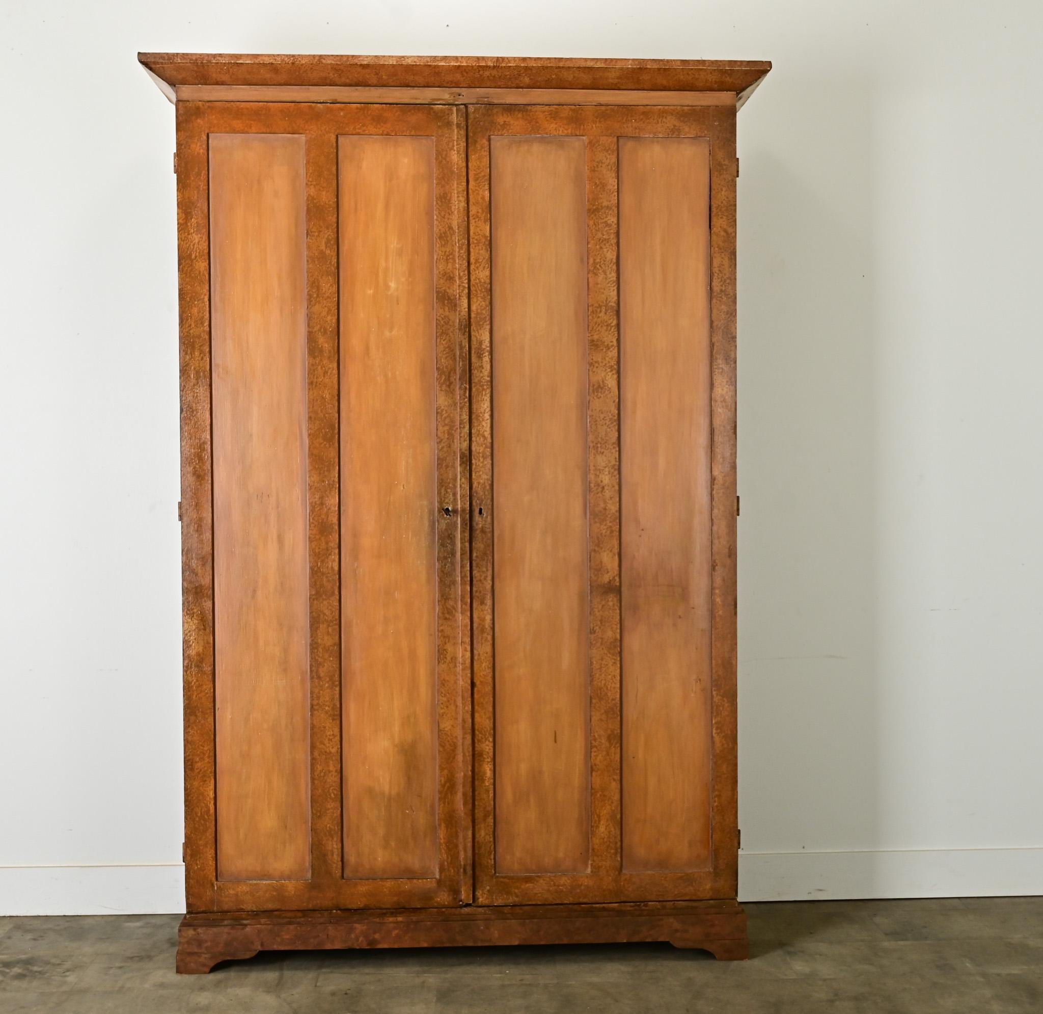 A painted Swedish armoire from the late 1800’s with clean lines and commanding presence. This solid pine wardrobe has its original sable-color pigment, applied in a trompe l’oeil effect to appear finley grained and without knots. The tall paneled