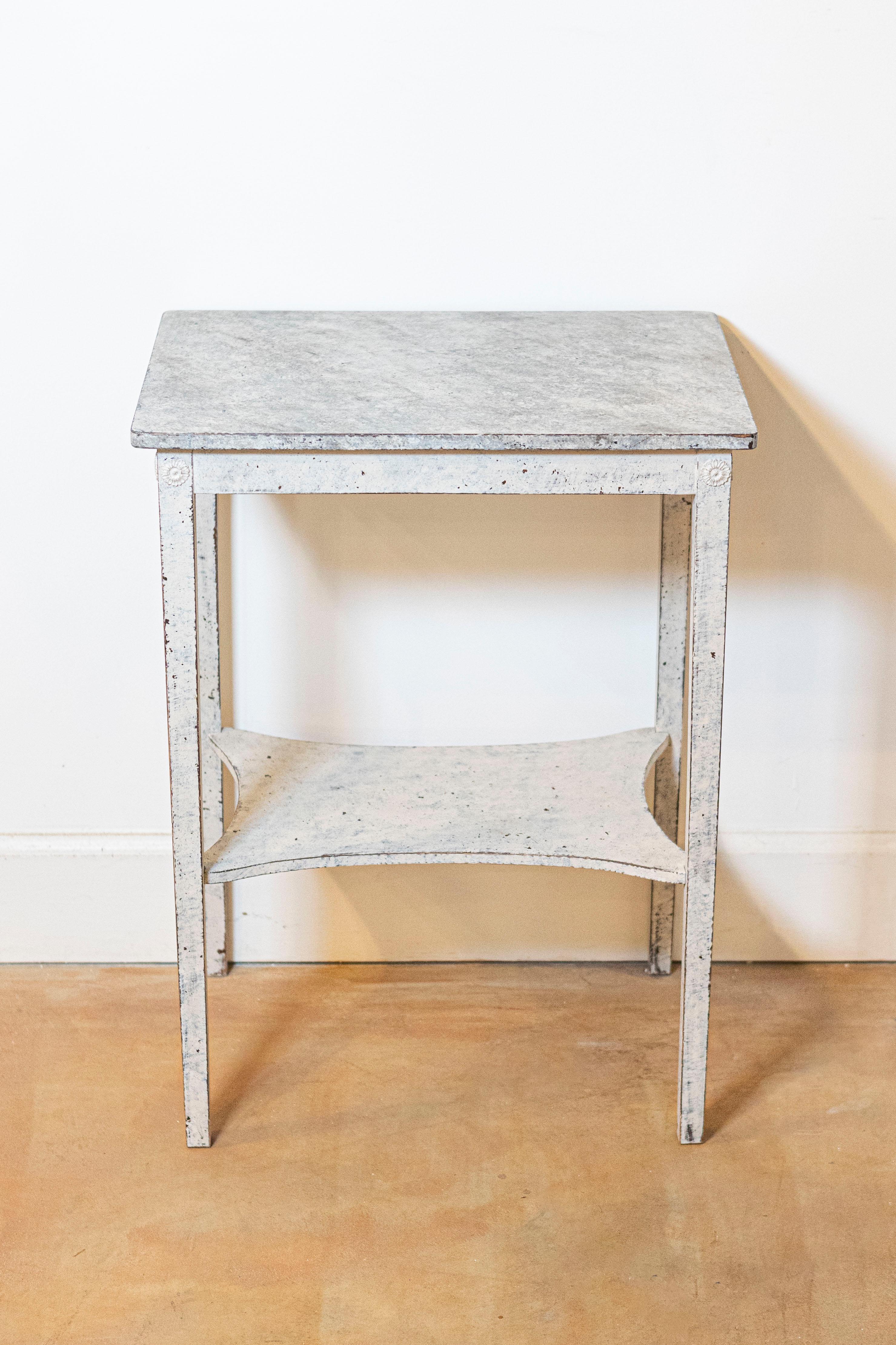 A Swedish painted side table from the 19th century, with marbleized top and in-curving low shelf. Created in Sweden during the 19th century, this painted side table features a rectangular faux marble top sitting above four straight legs adorned with