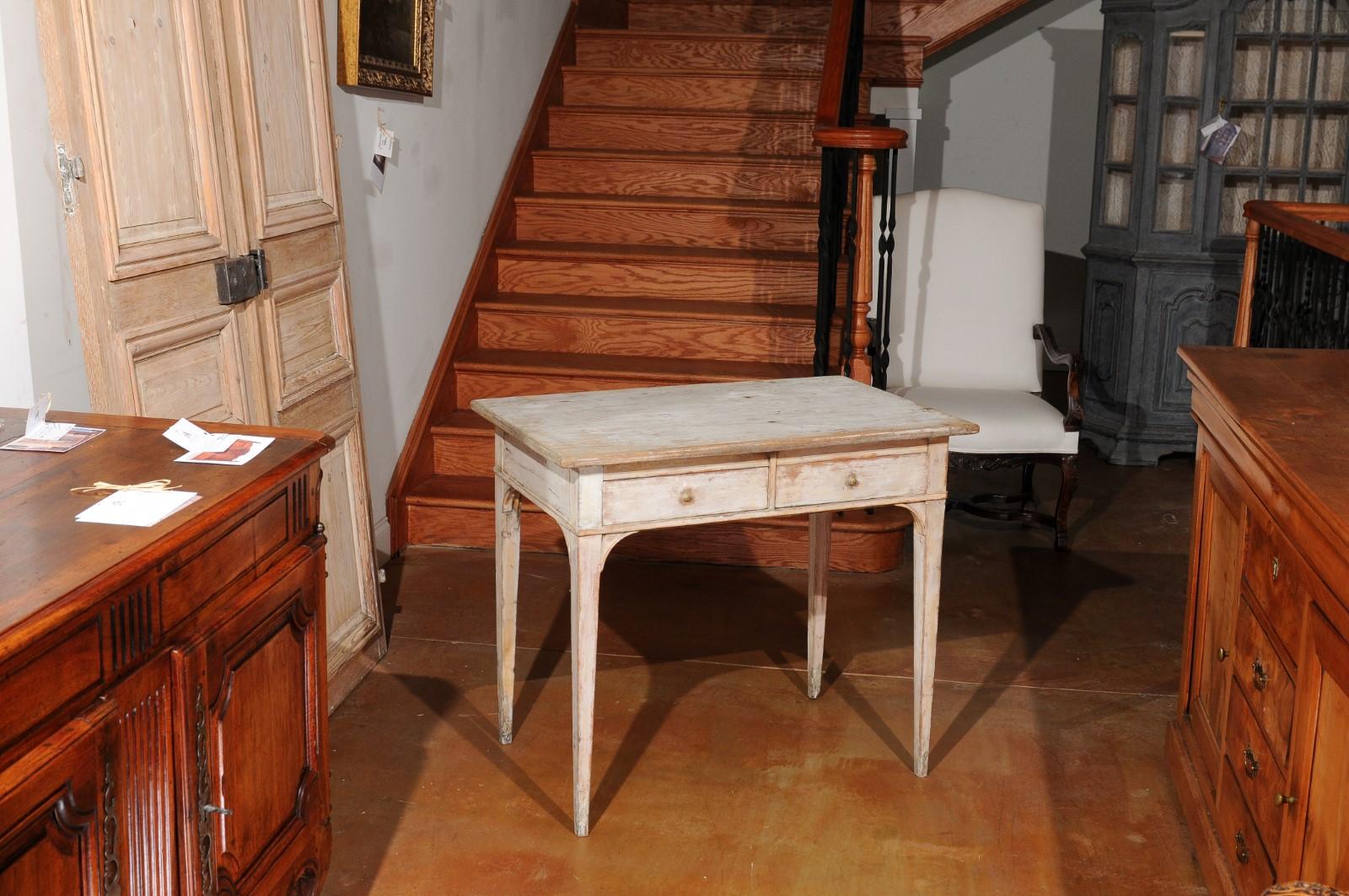 A Swedish painted wood desk from the 19th century, with two drawers, tapered legs and distressed finish. Created in Sweden during the 19th century, this painted desk features a rectangular top sitting above two drawers fitted with brass pulls. The