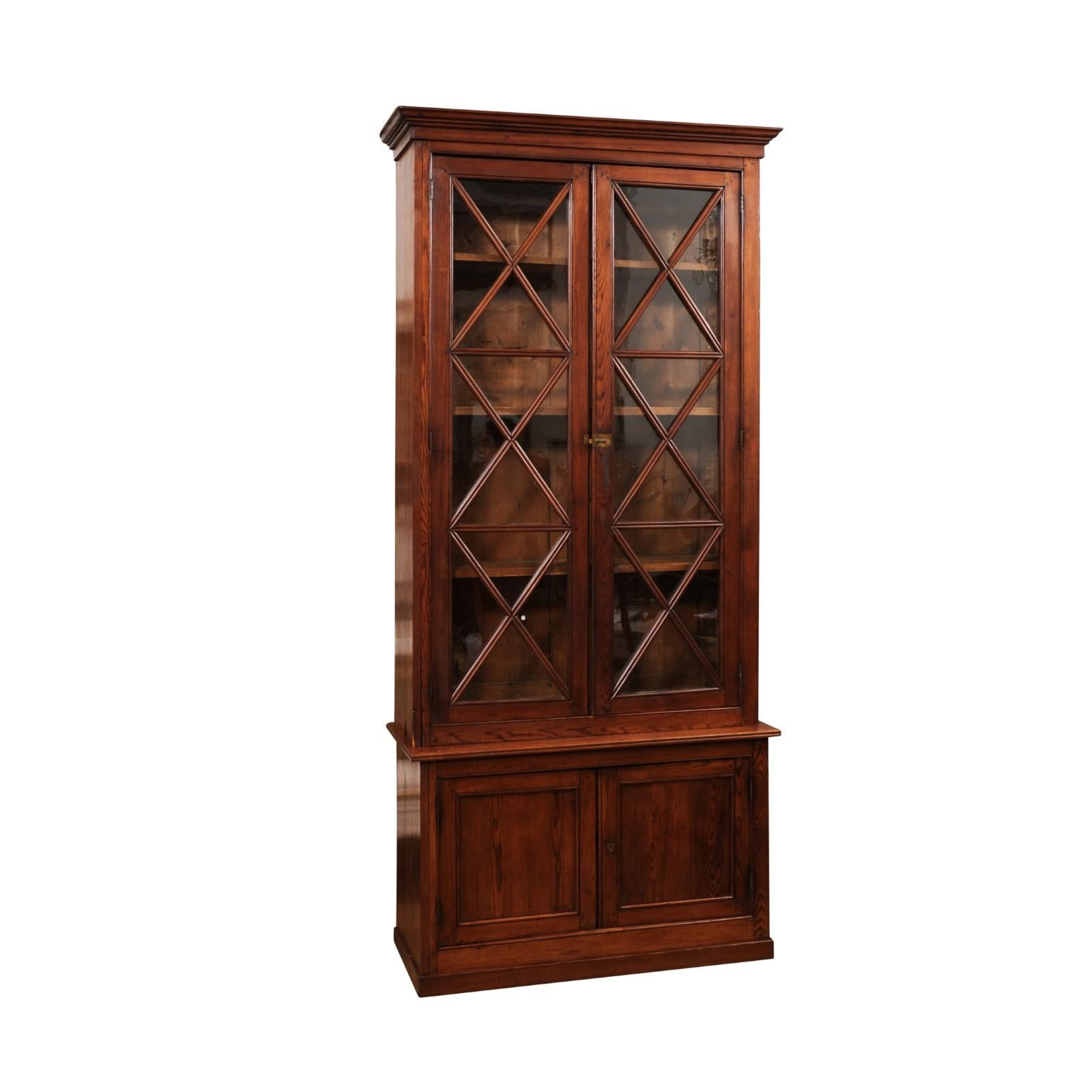 A Swedish walnut two-part vitrine cabinet from the 19th century with large glass doors and X-Form motifs. Step into the world of classic Swedish design with this elegant walnut two-part vitrine cabinet from the 19th century, a piece that perfectly