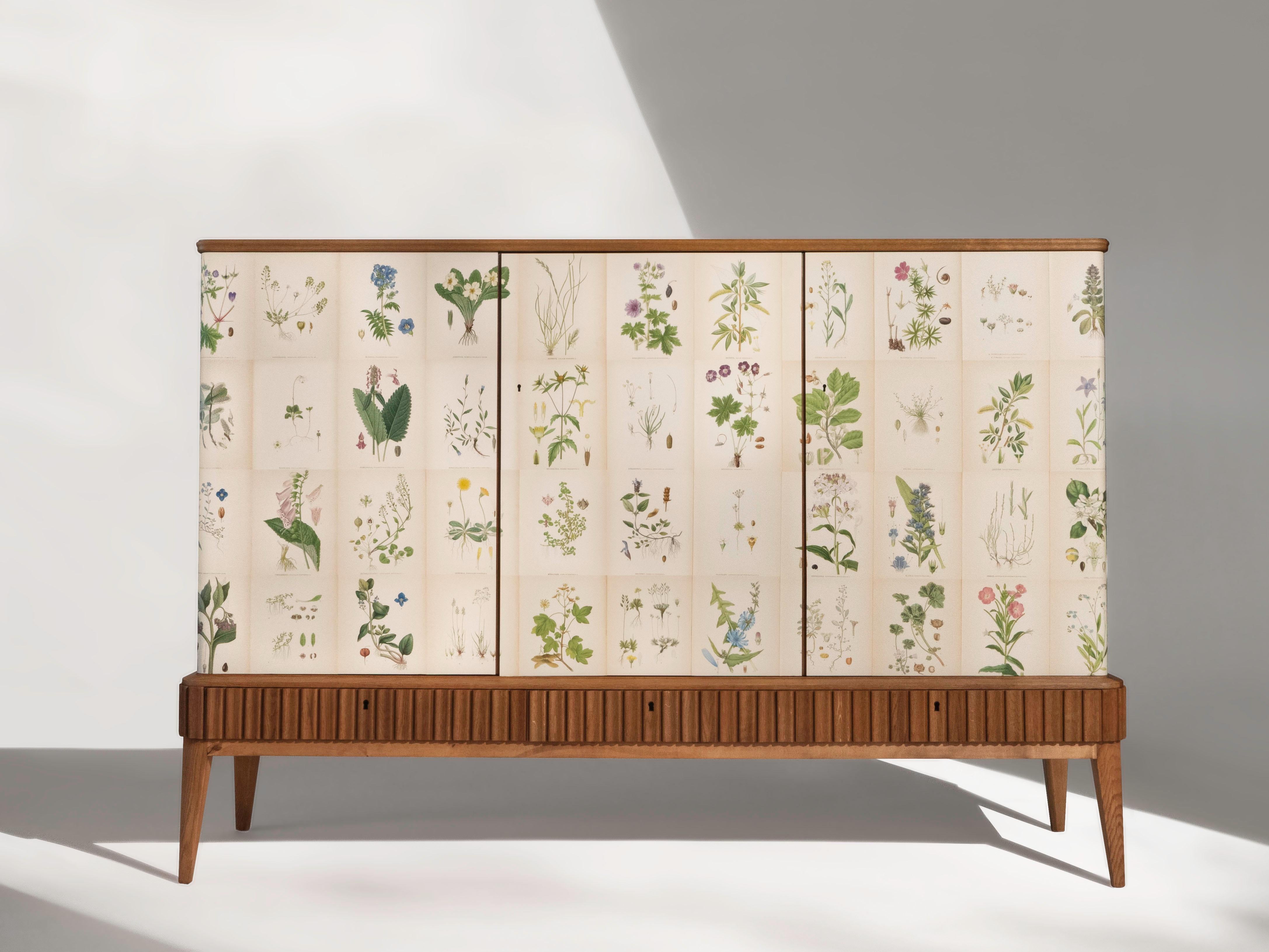 Buffet suédois à trois portes en chêne avec un plateau en acajou, vers les années 1950. Le meuble rectangulaire est recouvert des illustrations de la Flore de Norden de C.A.C. datant des années 1920. Lindman.

L'armoire comporte trois portes qui