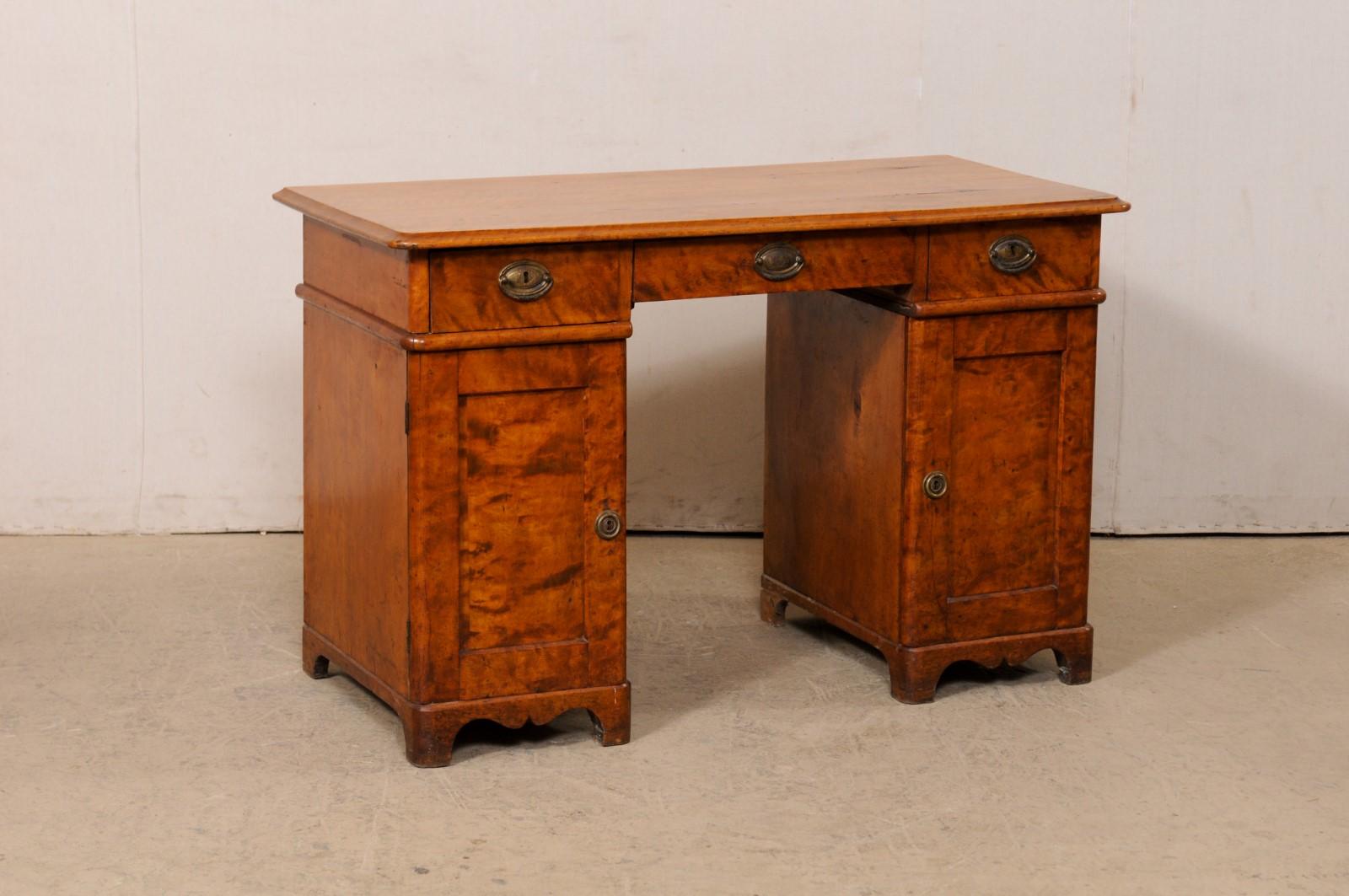 A Swedish pedestal curly birch desk, circa 1820-40. This antique desk from Sweden features a four foot long, rectangular-shaped top which overhangs the apron below that houses three drawers set horizontally at its underside, and resting upon on a