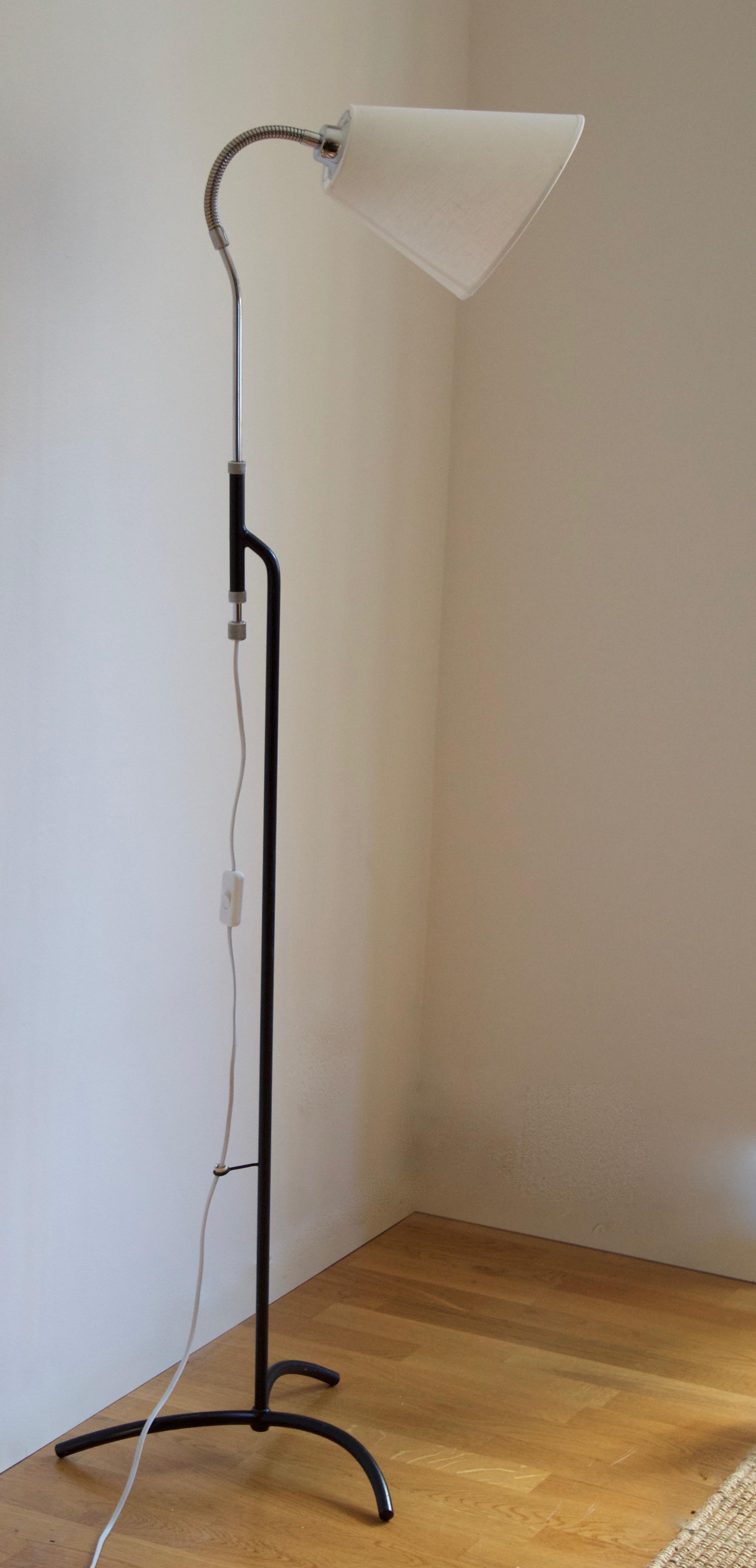 An adjustable functionalist floor lamp. Designed and produced in Sweden, 1940s-1950s. In black-lacquered metal and chromed steel. Brand new linen lampshade.