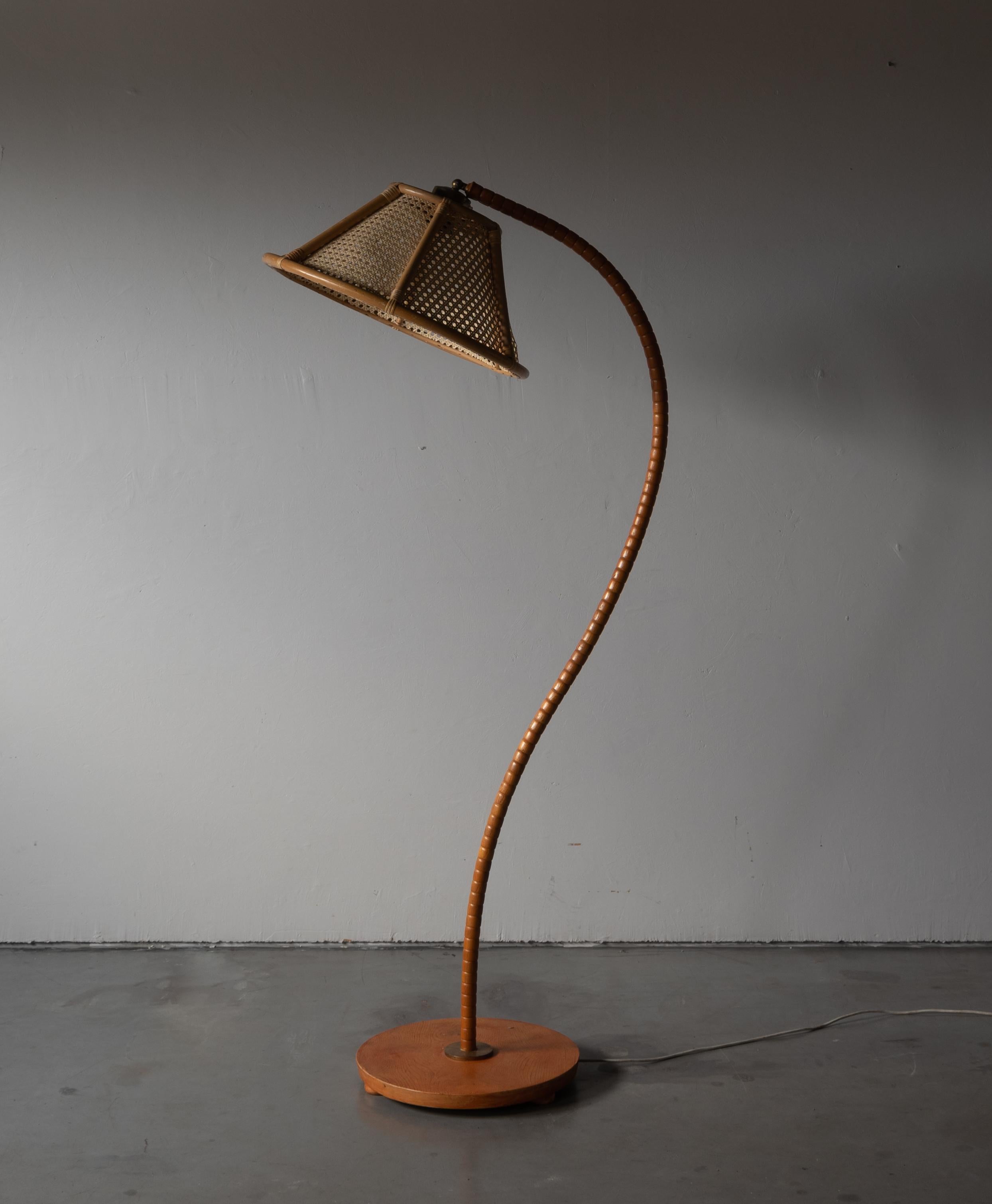 An adjustable organic floor lamp, designed and produced in Sweden, c. 1940s. With an assorted rattan/bamboo lampshade.
 