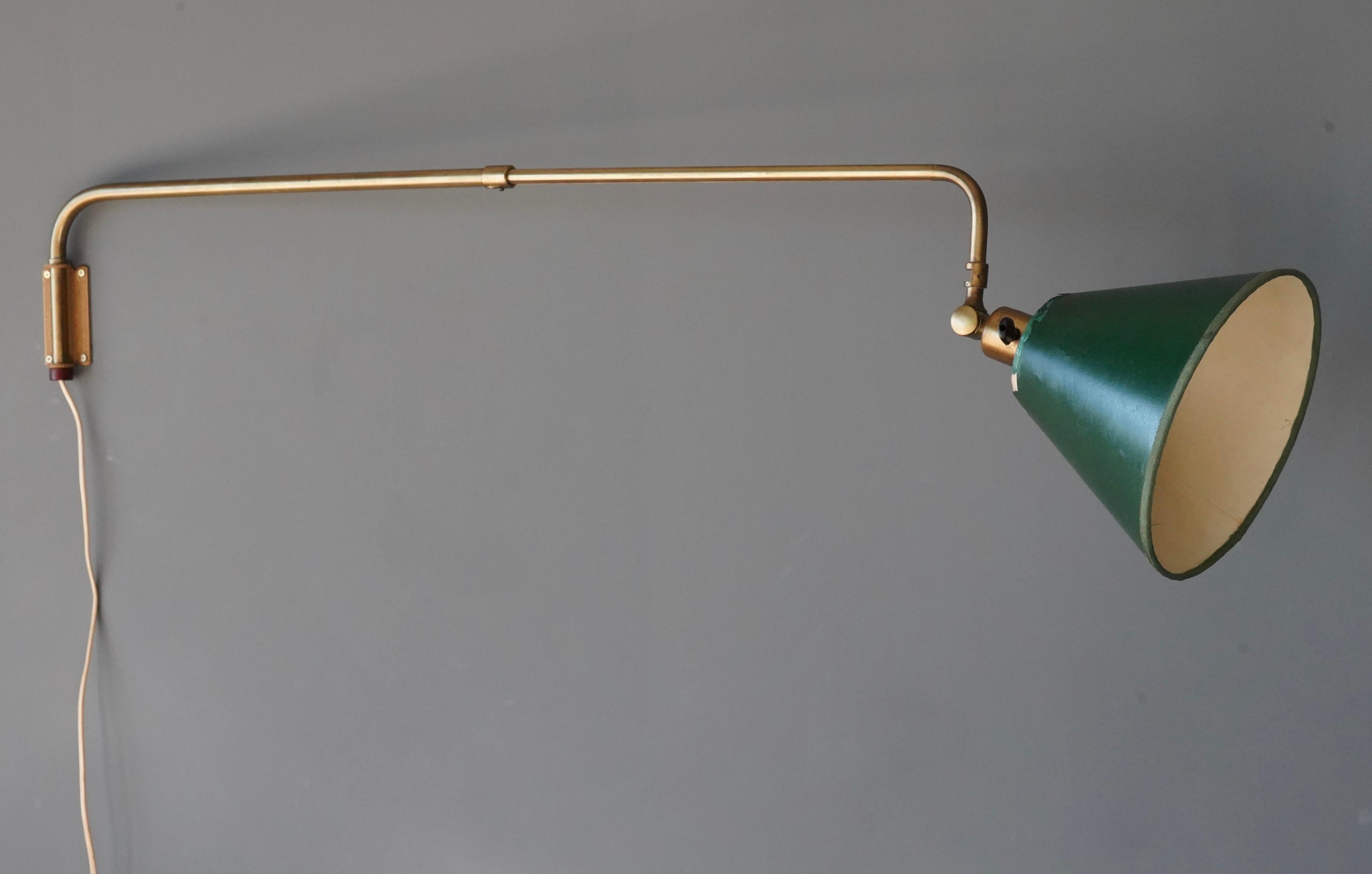 An adjustable organic wall light. In brass, with a vintage lampshade, likely original, in lacquered green fabric.

Dimensions are as pictured at the shortest position. Width can be extended to an additional 16 inches.