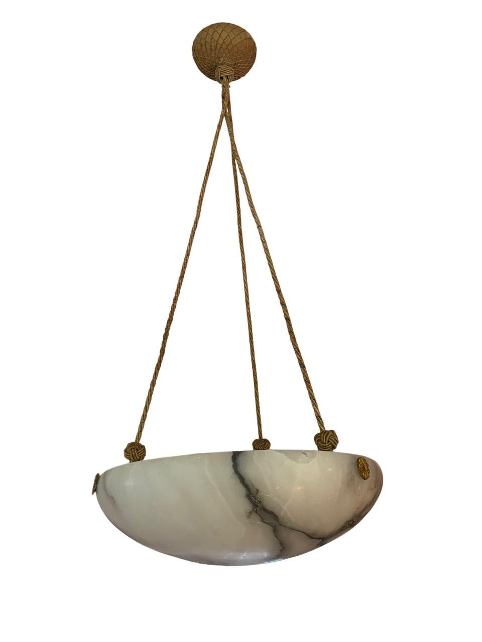 Elegante lámpara colgante de alabastro procedente de Suecia, fabricada en la década de 1940. La gran pantalla en forma de cuenco está tallada en alabastro macizo y presenta un llamativo veteado natural en suaves tonos blancos y grises. Está