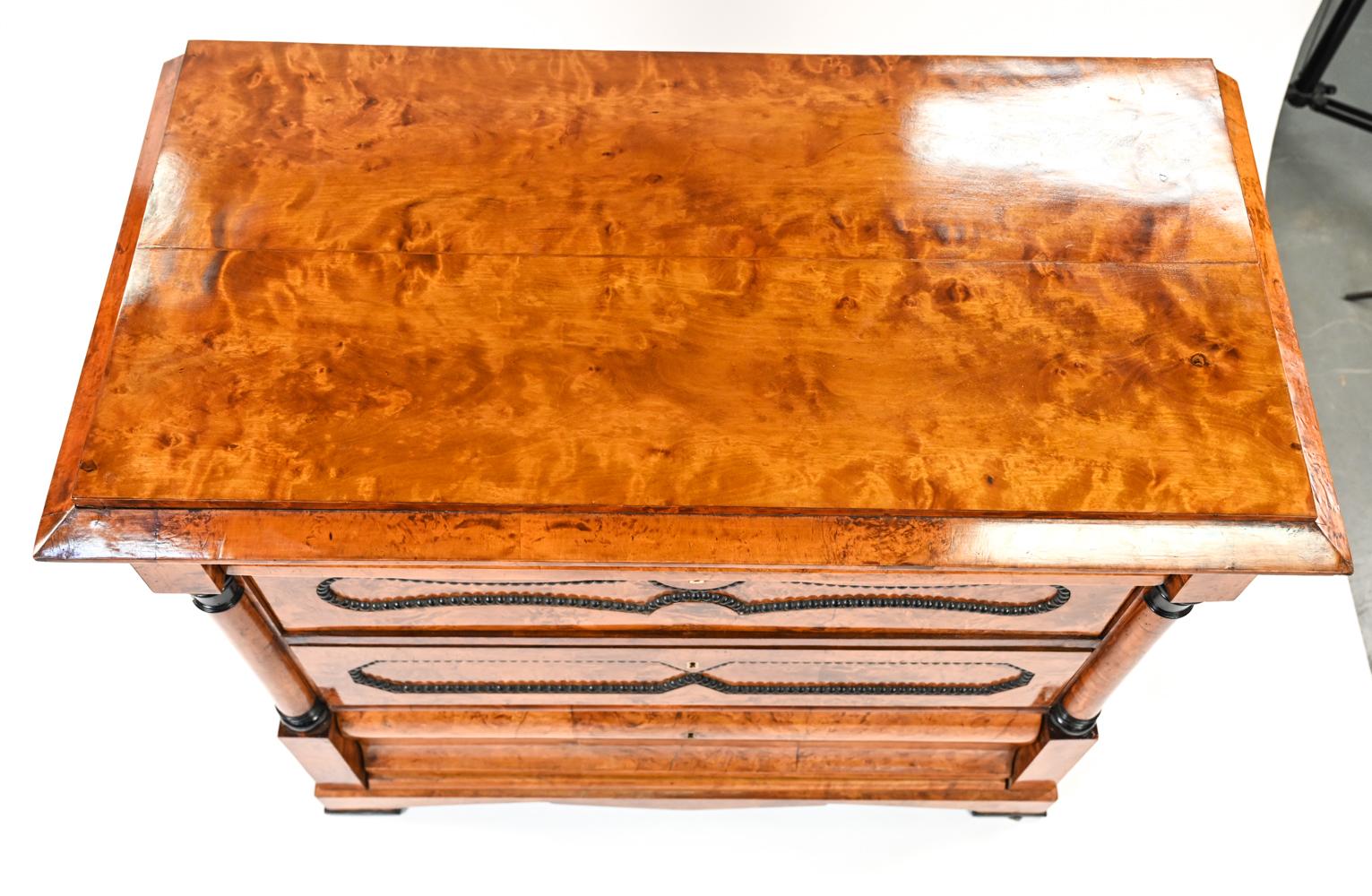 A handsome Swedish antique beechwood chest of drawers in the Biedermeier style with beautiful grain and finish, featuring ebonized and beaded details.