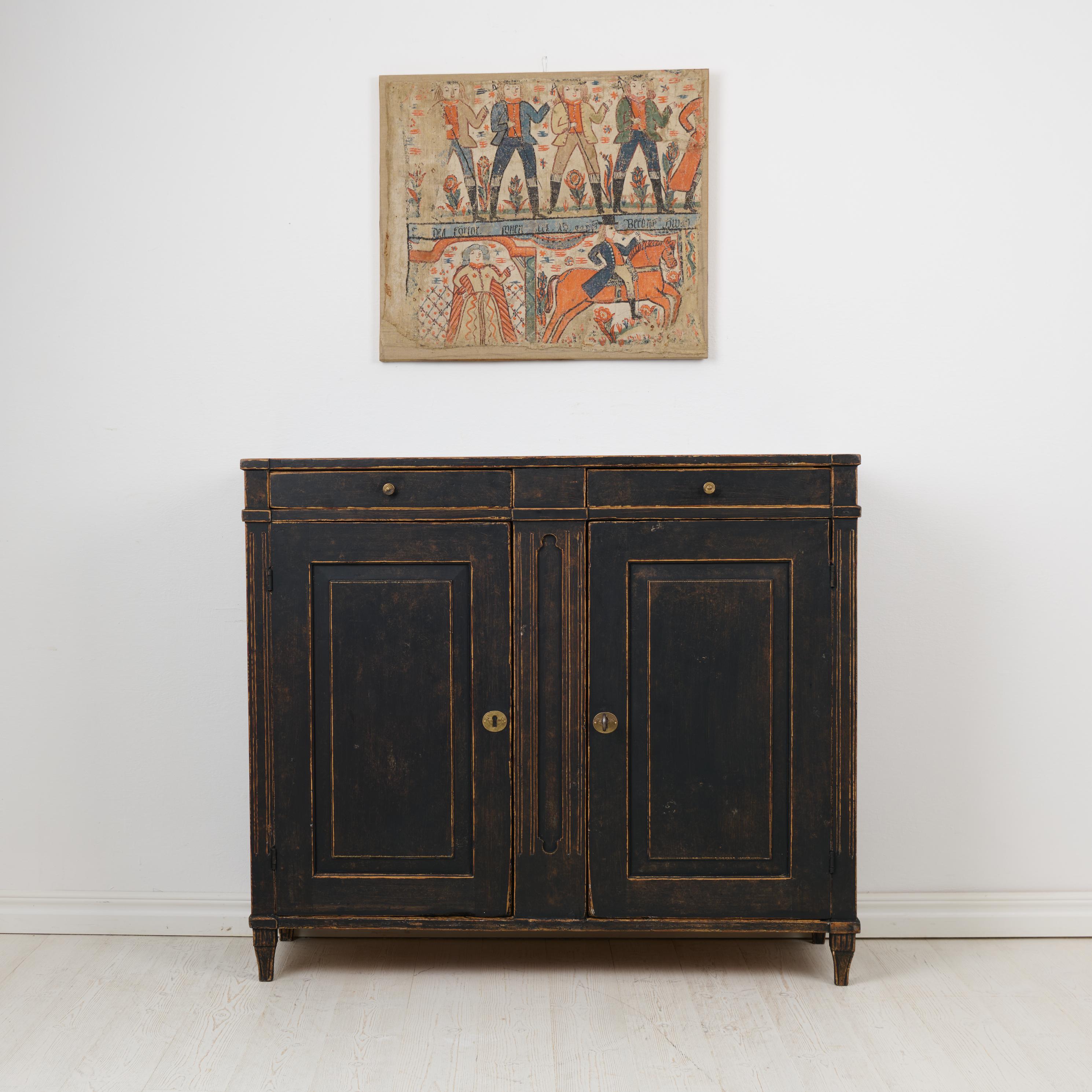 Swedish country antique sideboard from the gustavian period during the late 1700s. The sideboard has a classic straight shape with double doors and two drawers. Tall tapered legs also very typical to the gustavian period. Working lock and key.