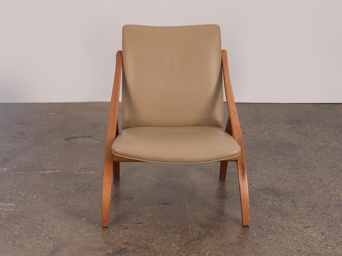 Swedish armless sculpted lounge chair. An unusual chair design, understated and elegant with a low-slung form. Taupe leather upholstery is in very good condition, soft to the touch. No stains, tears, and is very pliable. Cushion is supportive and