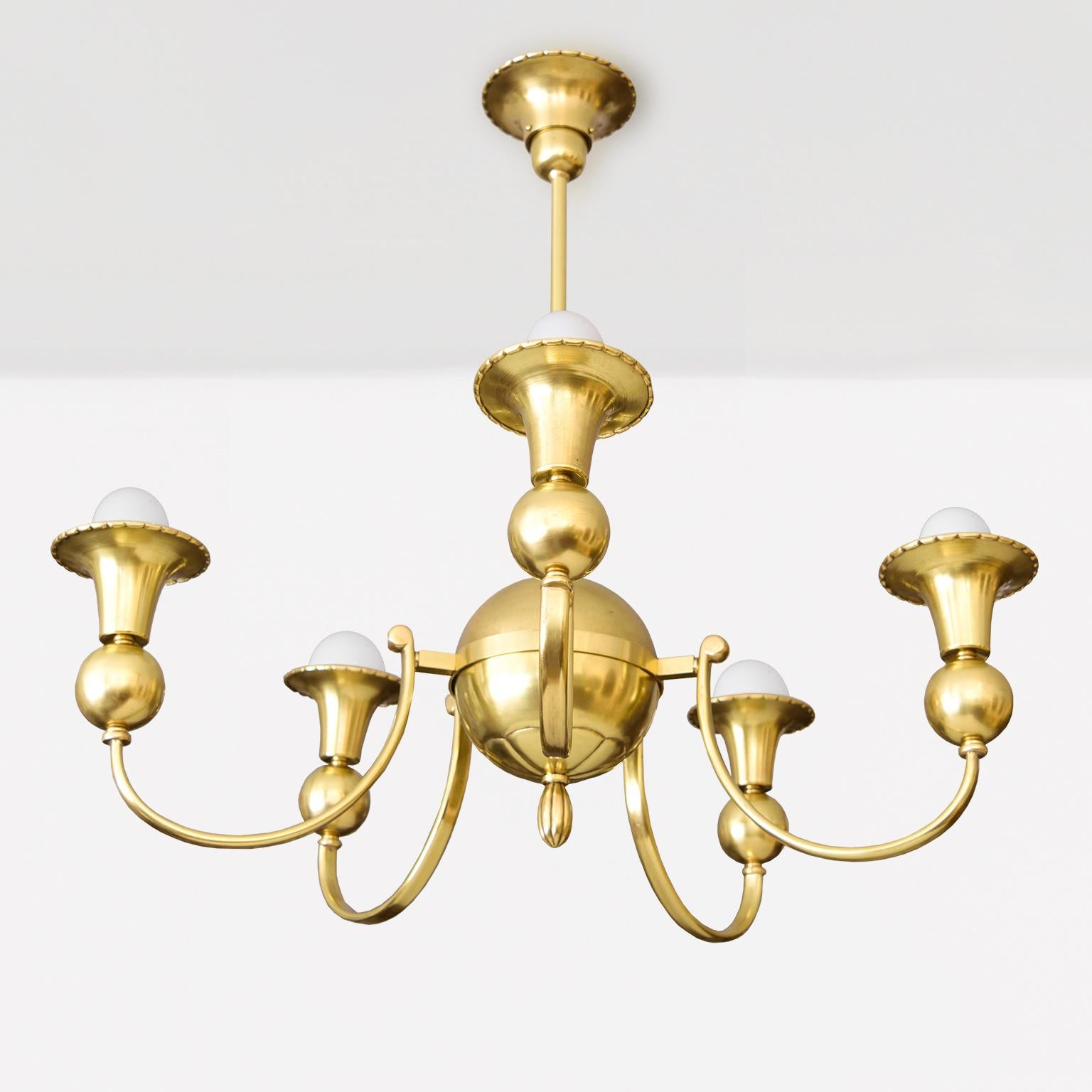 Un lampadario svedese in ottone Art Deco del 1930 circa. L'apparecchio presenta 5 bracci ad arco rovesciato che sostengono bobeches a forma di imbuto montate su sfere di ottone. I bracci si irradiano da un globo di ottone con l'impronta del